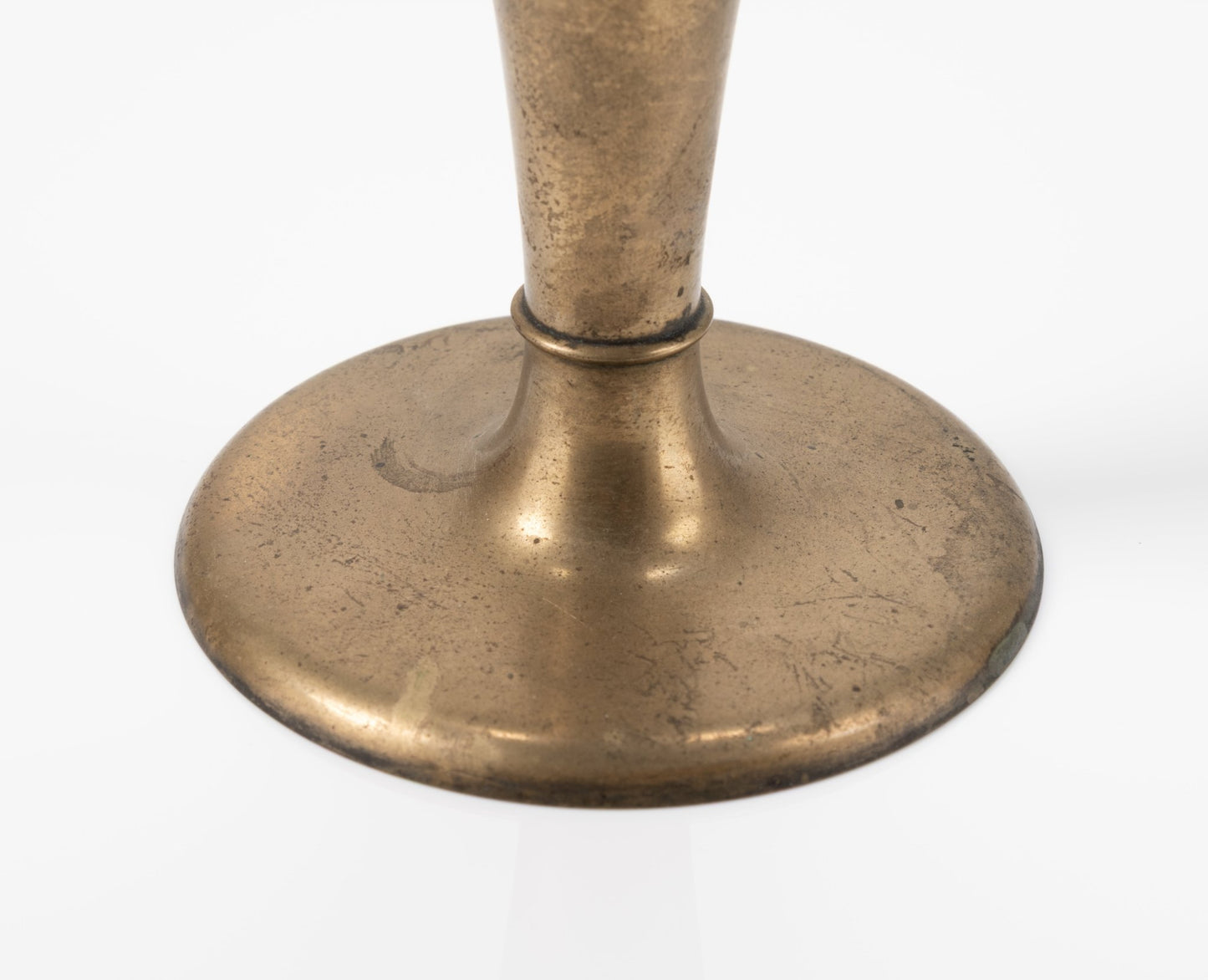 Close-up of 1930s Dirigold brass metal bud vase base with warm patina and 3.75-inch wide stable design on white background