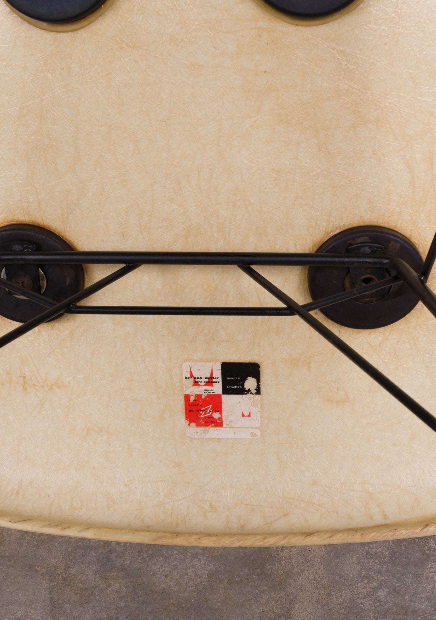 Underside view of vintage Eames rope-edge fiberglass rocker showing original Herman Miller label and black metal base details