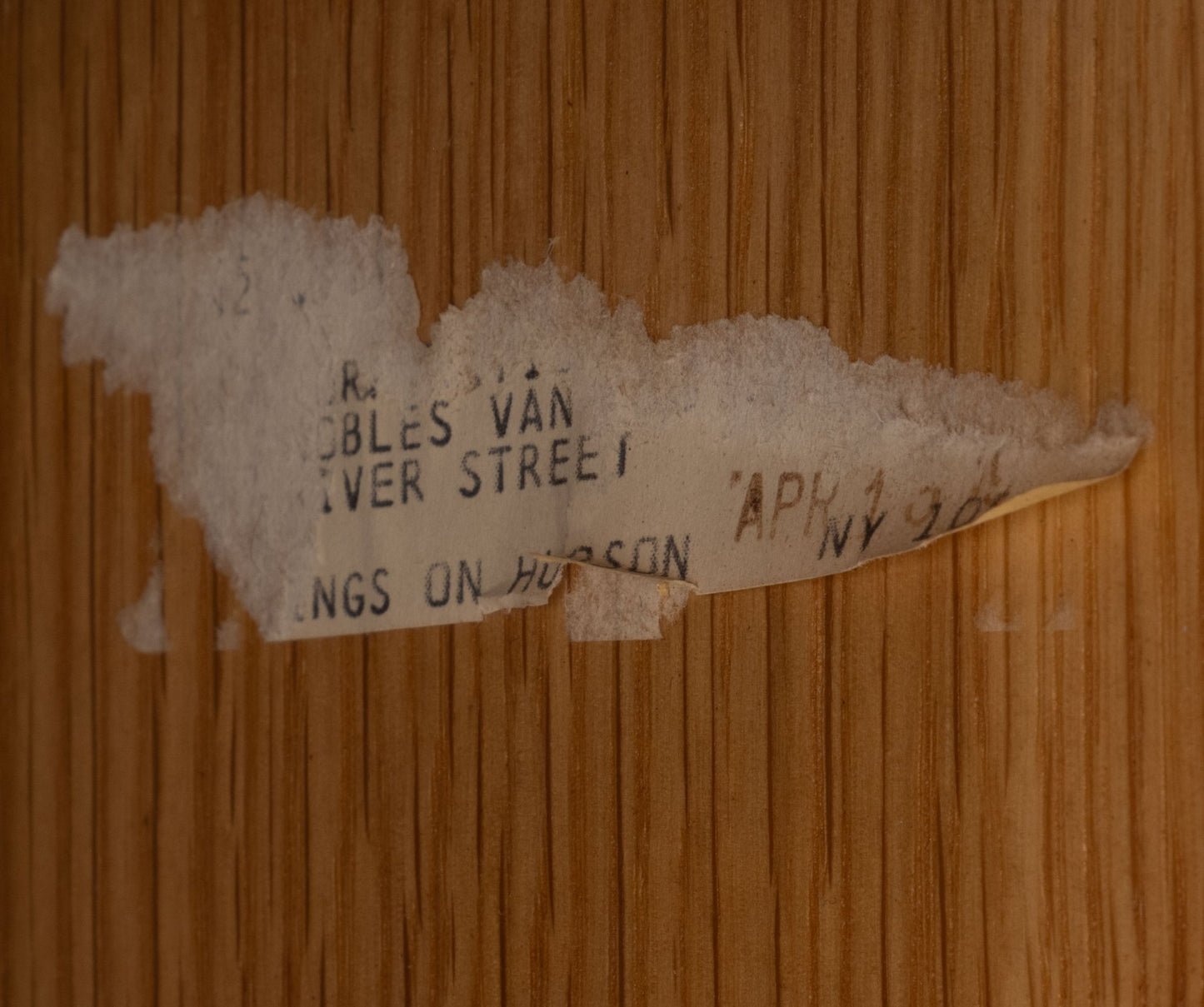 Close-up of worn vintage paper label with partial text on mid-century wood surface background