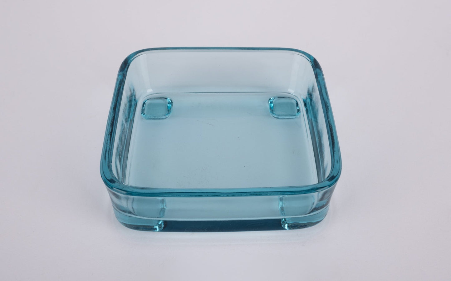 Square light blue glass insert bowl with rounded corners and raised feet on white background