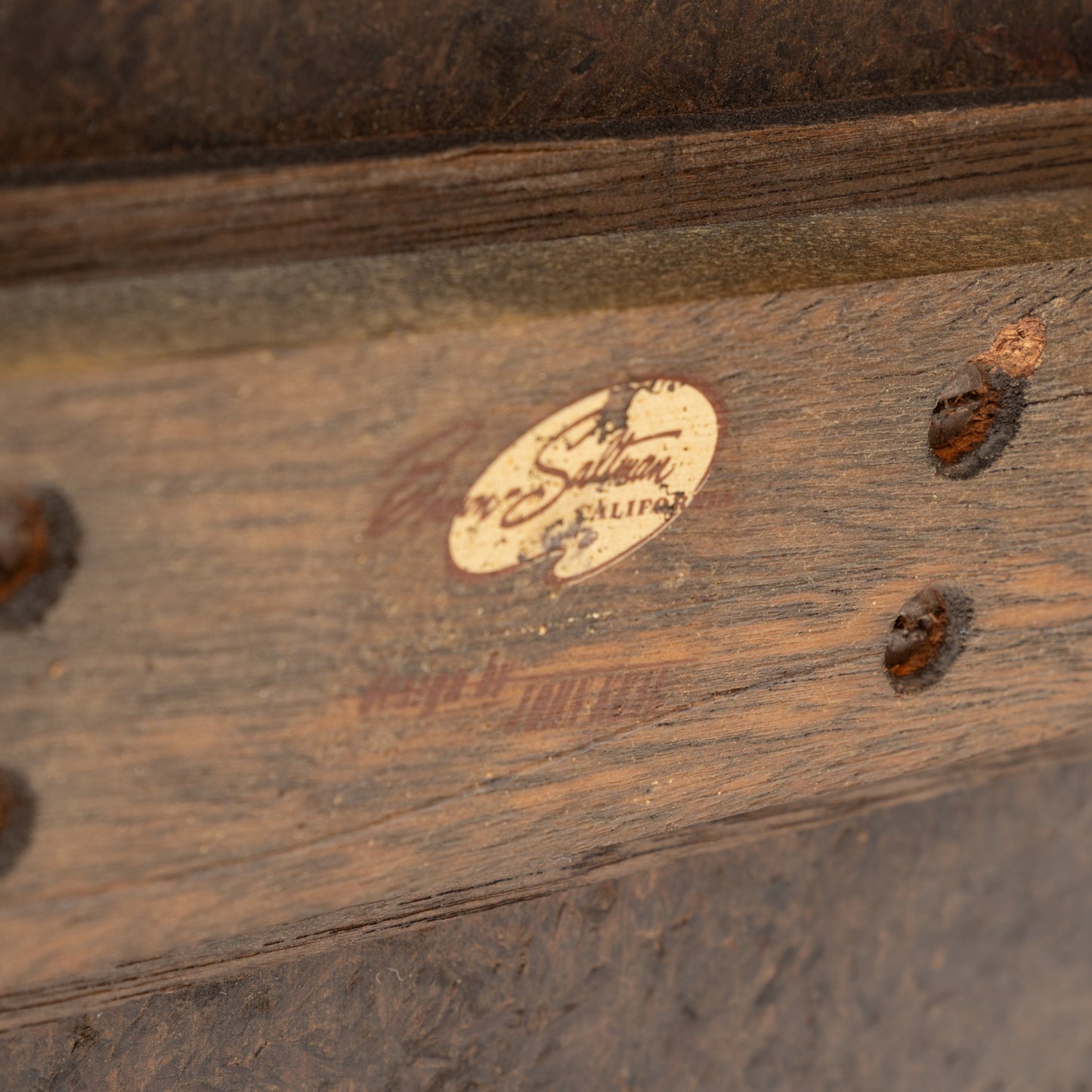 John Keal 'Outrigger' Coffee Table close-up showing the aged wooden frame with visible screws and a partially worn label, emphasizing its vintage mid century modern character.