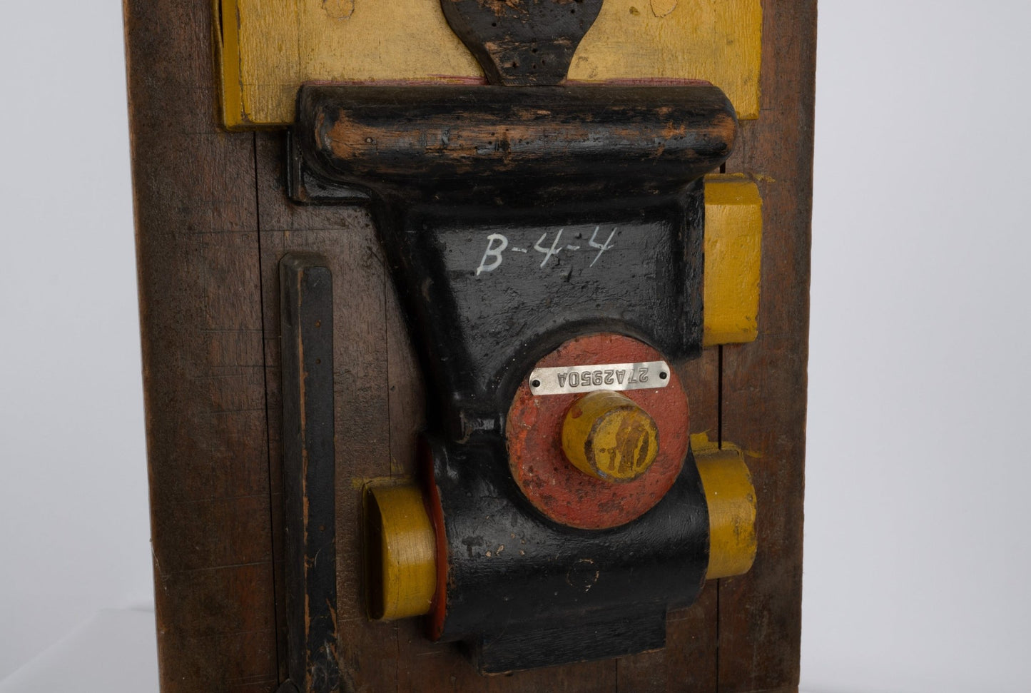 Two-sided wooden industrial machine mold sculpture with metal handle and vibrant patina on neutral background