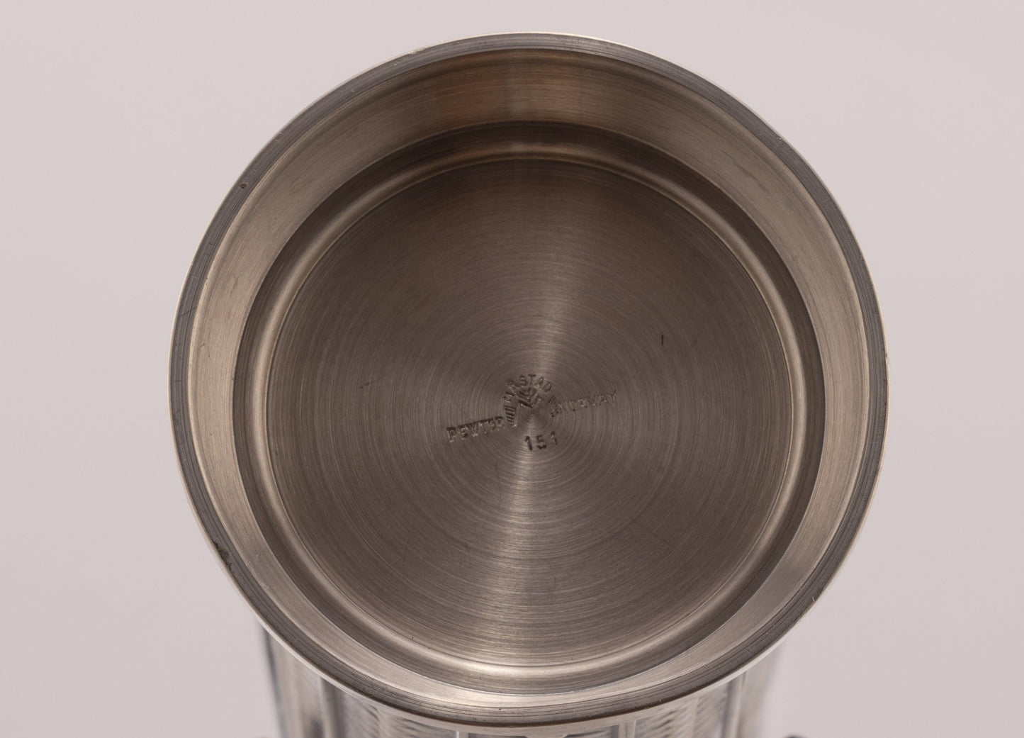 Top view of cylindrical Mastad pewter vase with engraved diamond-shaped column pattern and maker's mark on bottom