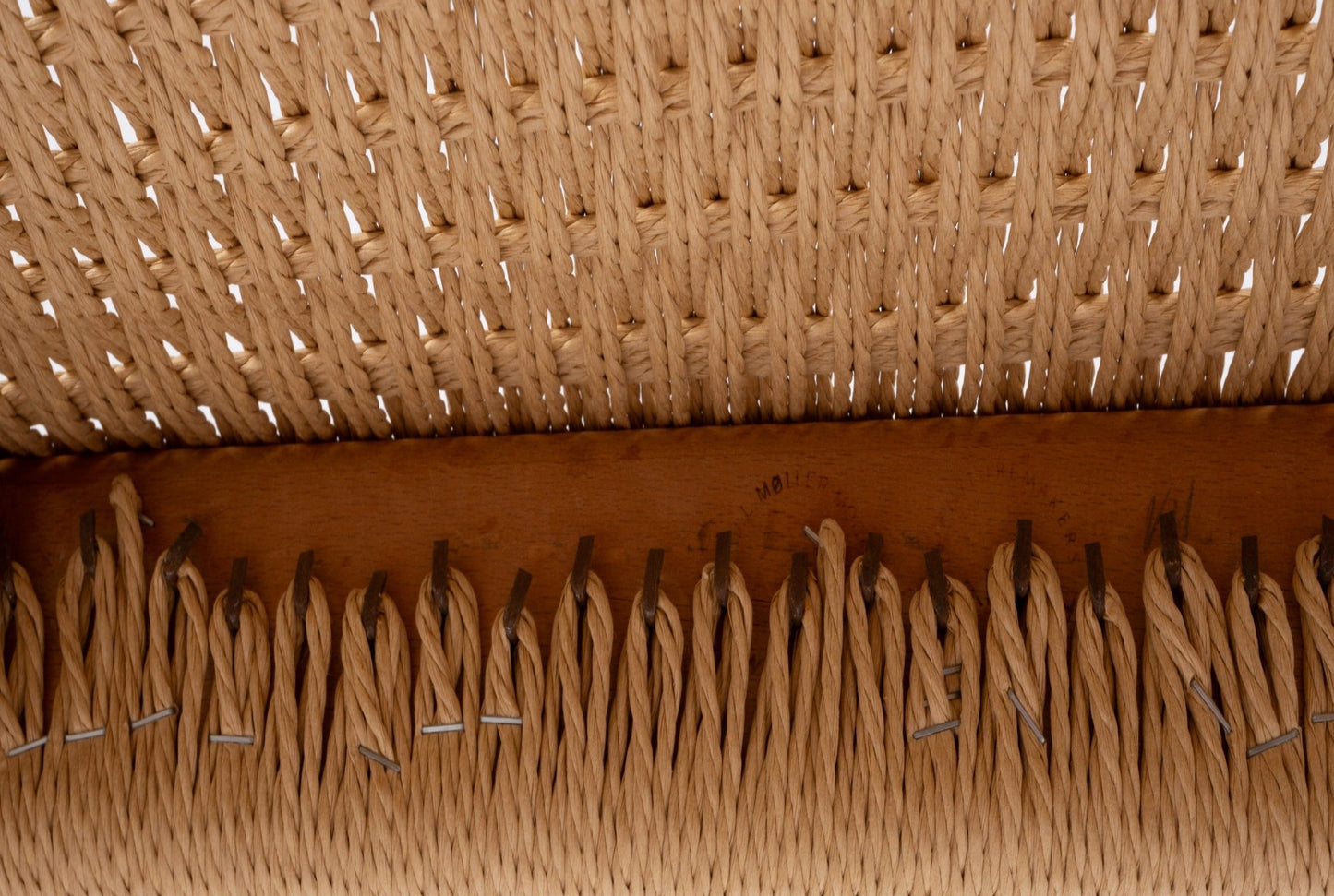 Close-up of woven Danish cord seat with solid teak frame and Niels Moller signature stamp on chair underside.