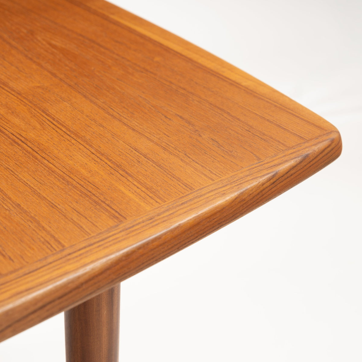 Rastad & Relling Extension Dining Table close detail of a rounded teak corner with rich wood grain and tapered leg in mid century modern furniture style