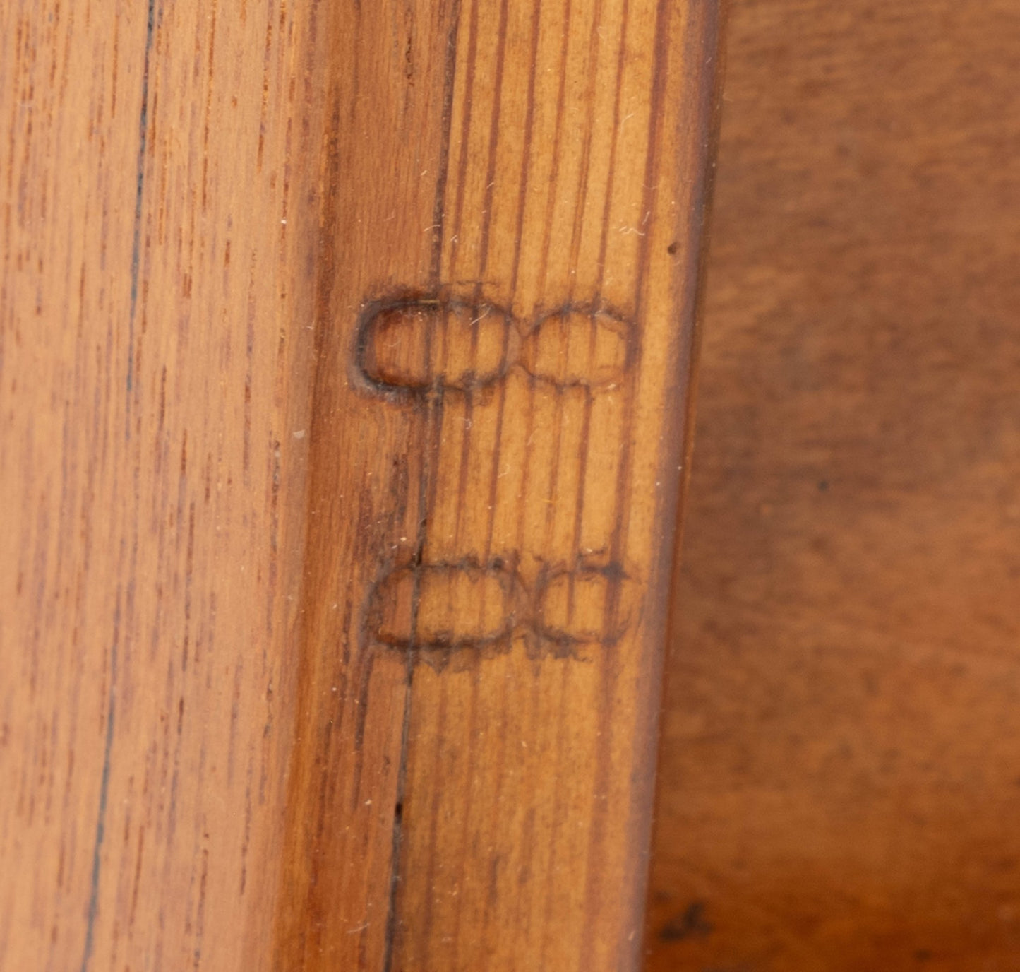Close-up of wooden underside of teak side table showing stamped number "88" on the edge.
