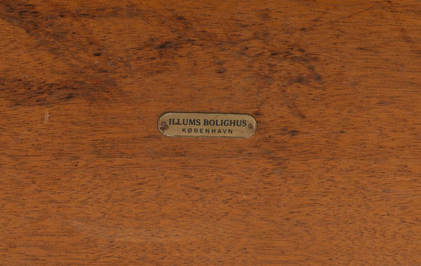 Close-up of brass Illums Bolighus label on rosewood surface of Yngvar Sandstrom coffee table for Seffle Mobelfabrik