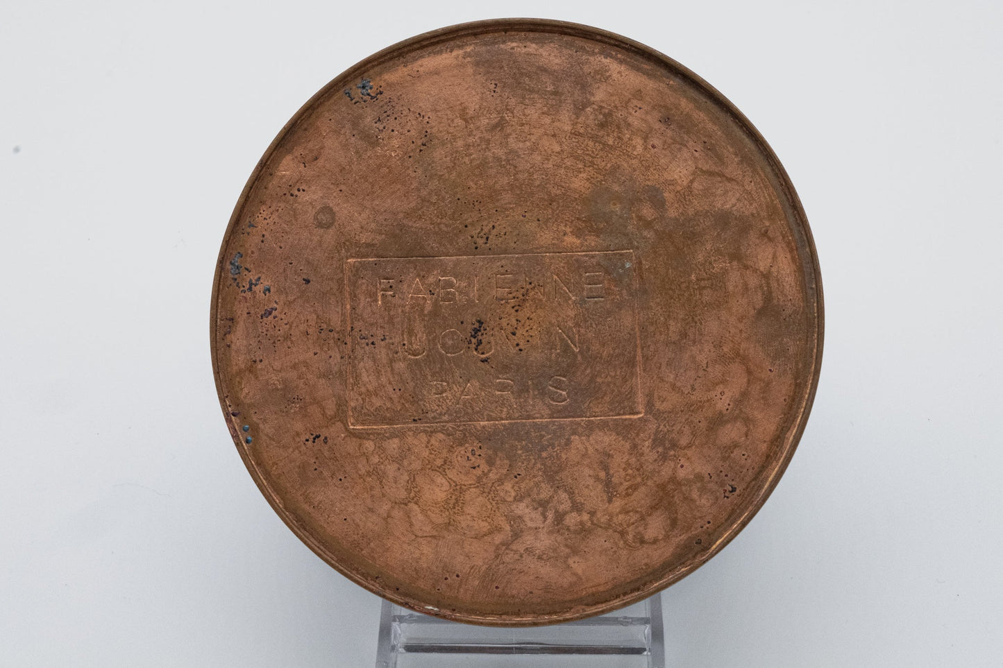 Bottom view of Fabienne Jouvin Paris stamped on patinated copper surface of round canister lid