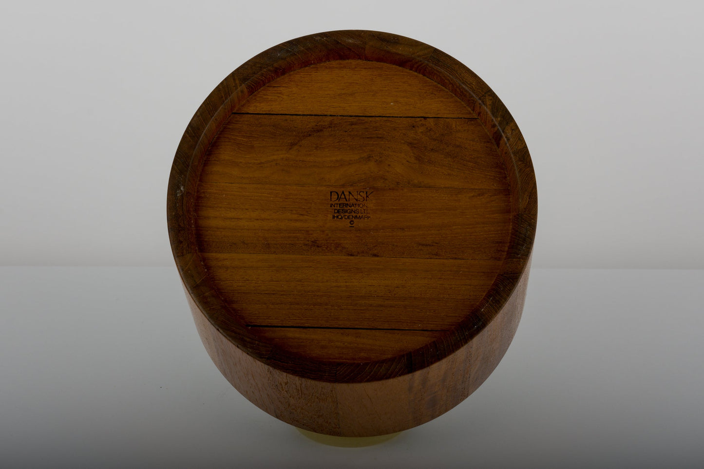 Bottom view of Jens Quistgaard teak ice bucket from the 1970s with Dansk Denmark maker’s mark on a reflective surface
