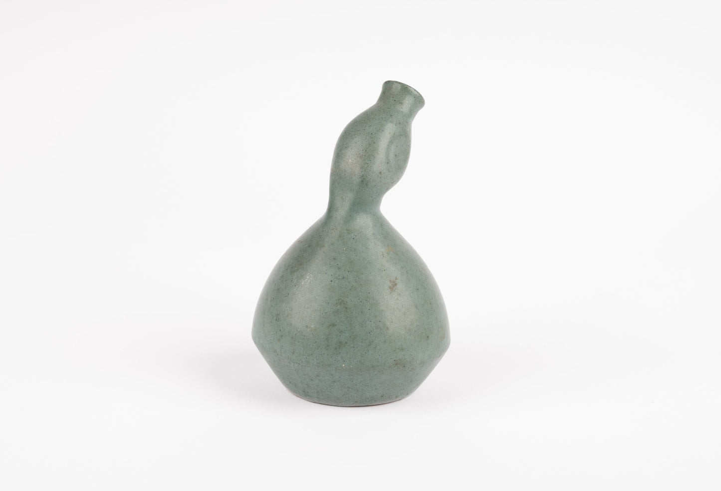 Abstract celadon studio pottery vase with gently swelling body and tilted neck on white background