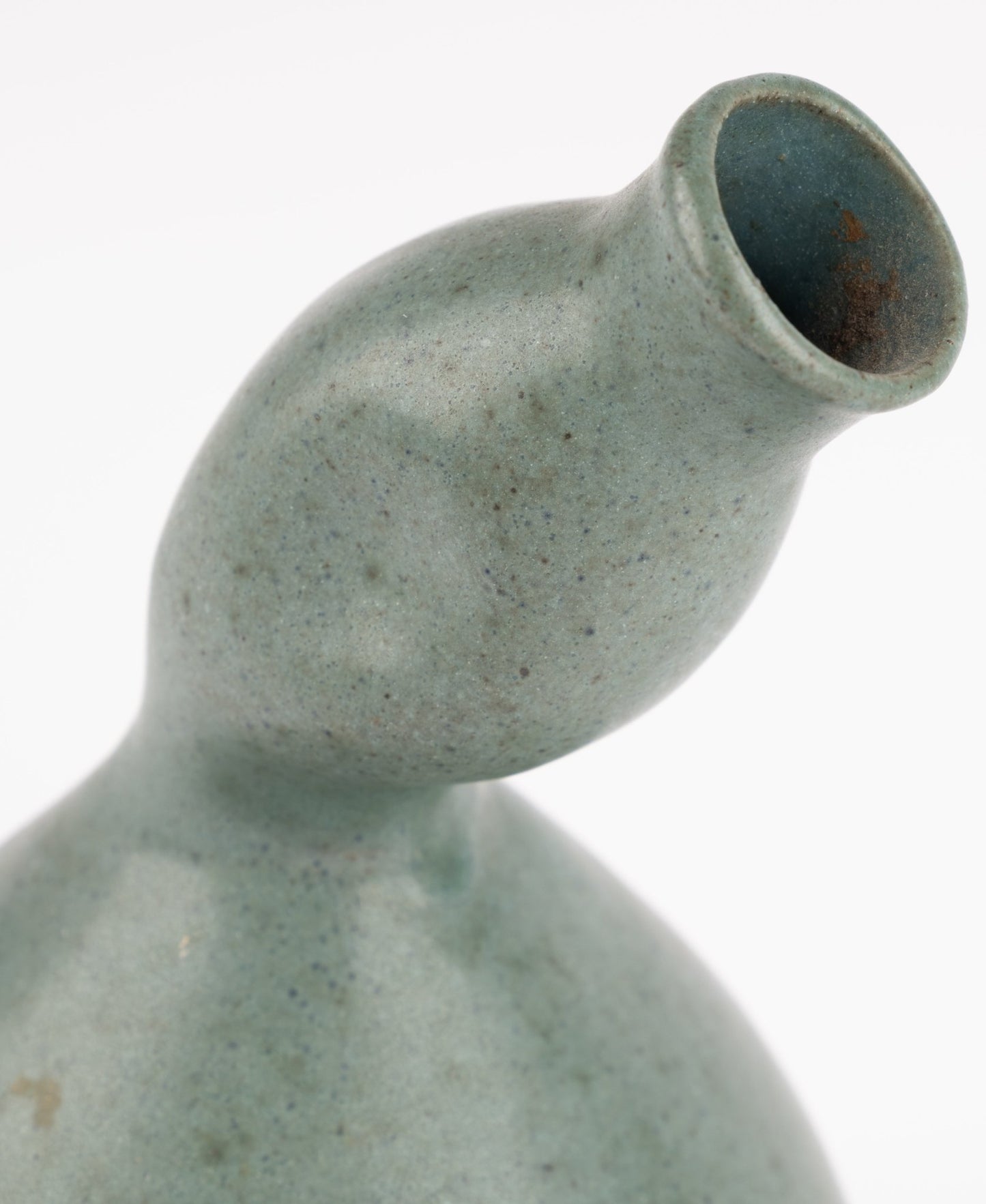 Close-up of abstract celadon studio pottery vase with gently swelling body and tilted neck on white background