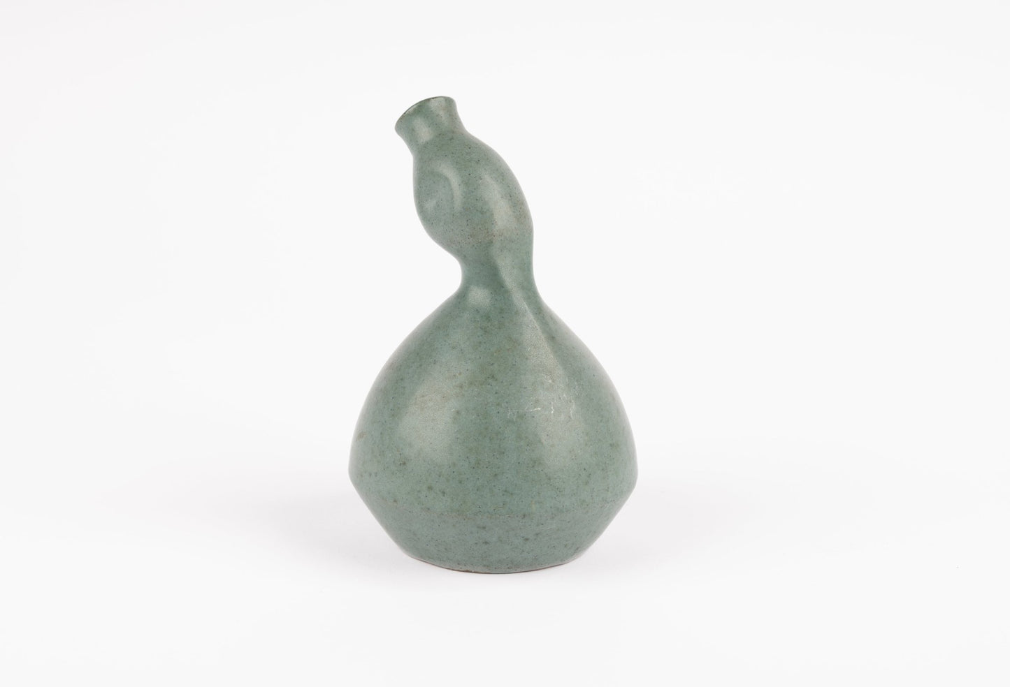 Abstract celadon-green studio pottery vase with gently swelling body and tilted neck on white background