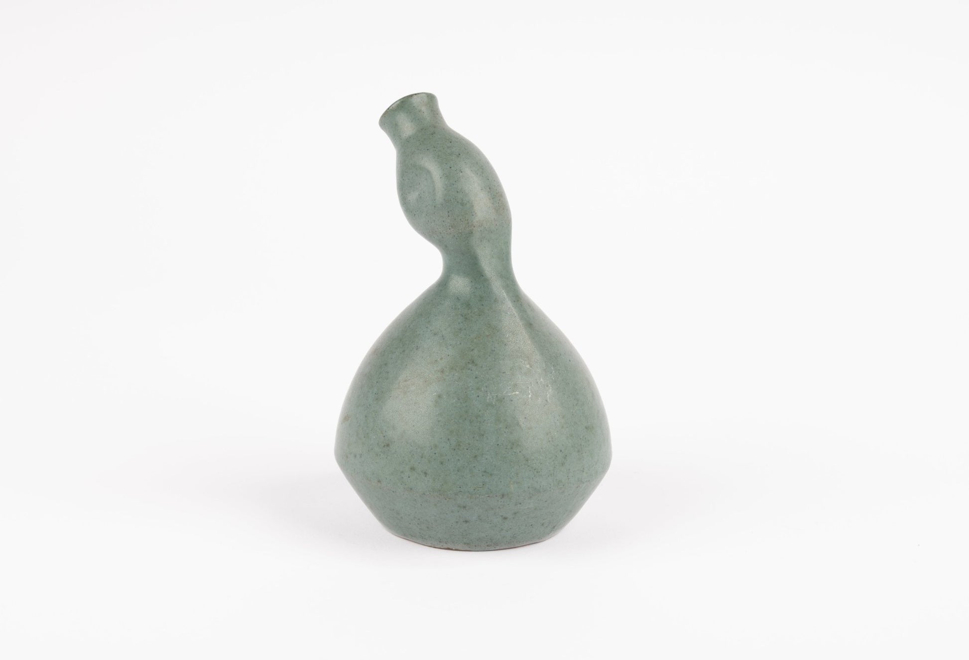 Abstract celadon-green studio pottery vase with gently swelling body and tilted neck on white background