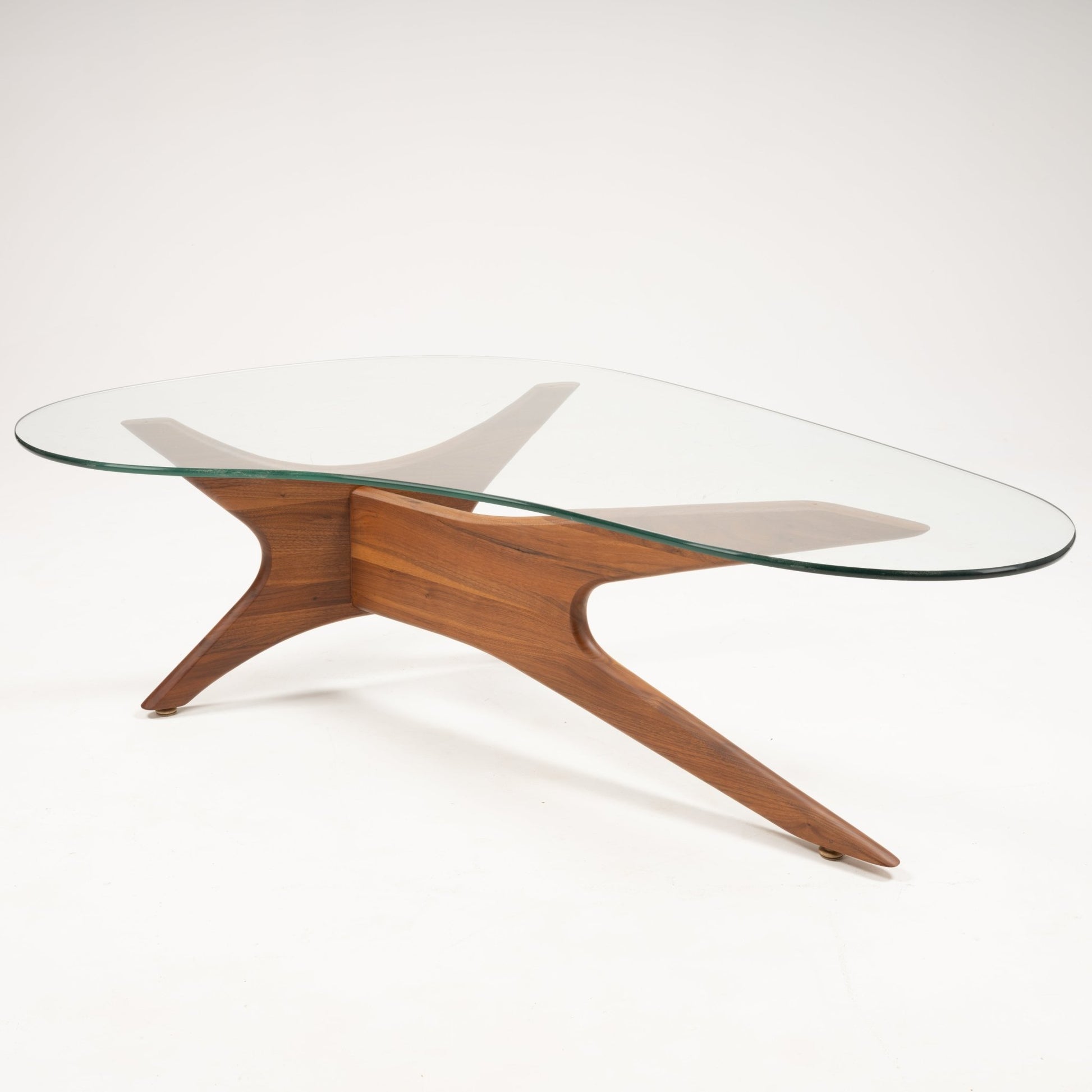 Organic-shaped clear glass top coffee table with sculptural solid walnut base featuring four outward curved legs