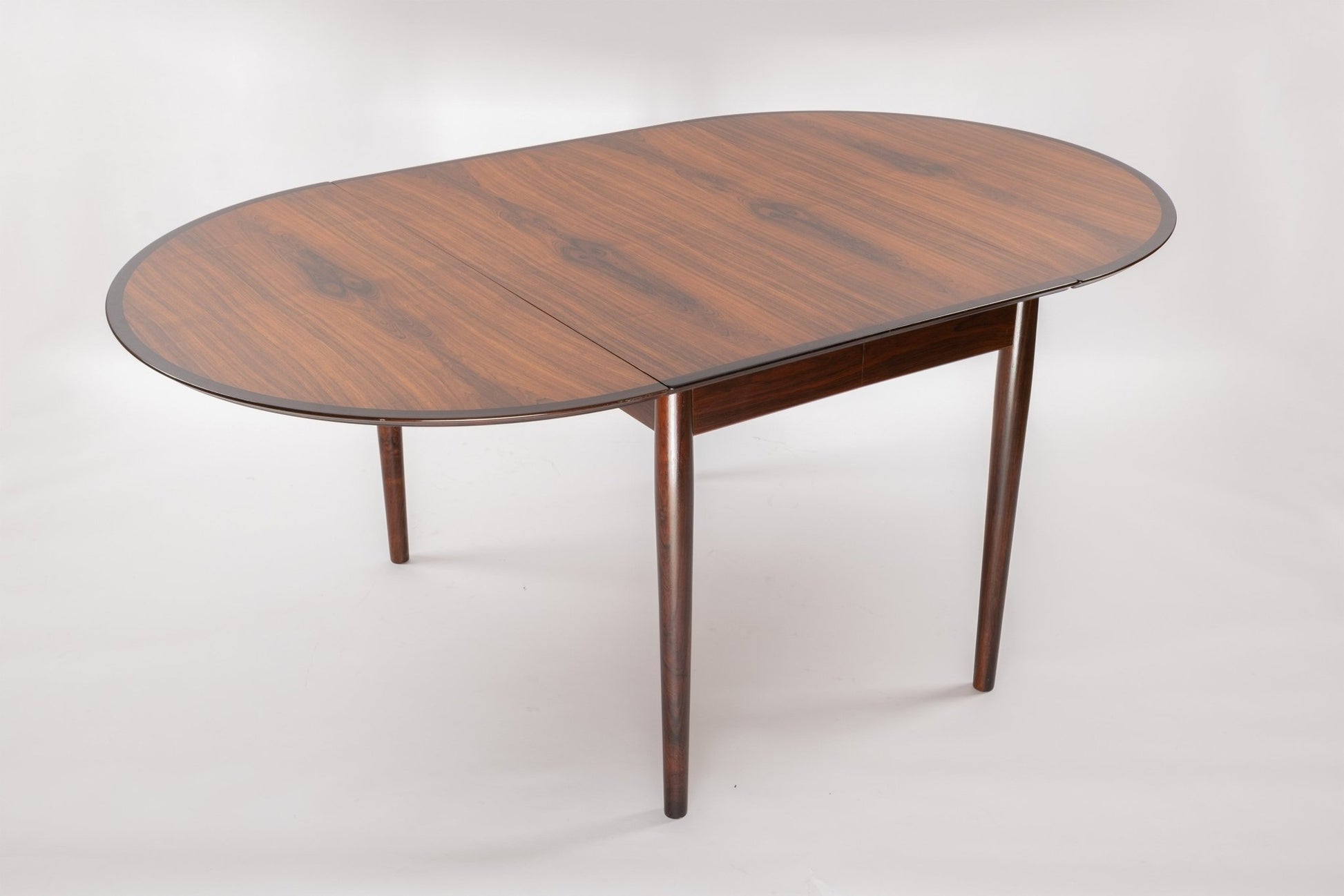 Mid-century modern Arne Vodder rosewood drop leaf dining table with tapered legs and expandable top on white background