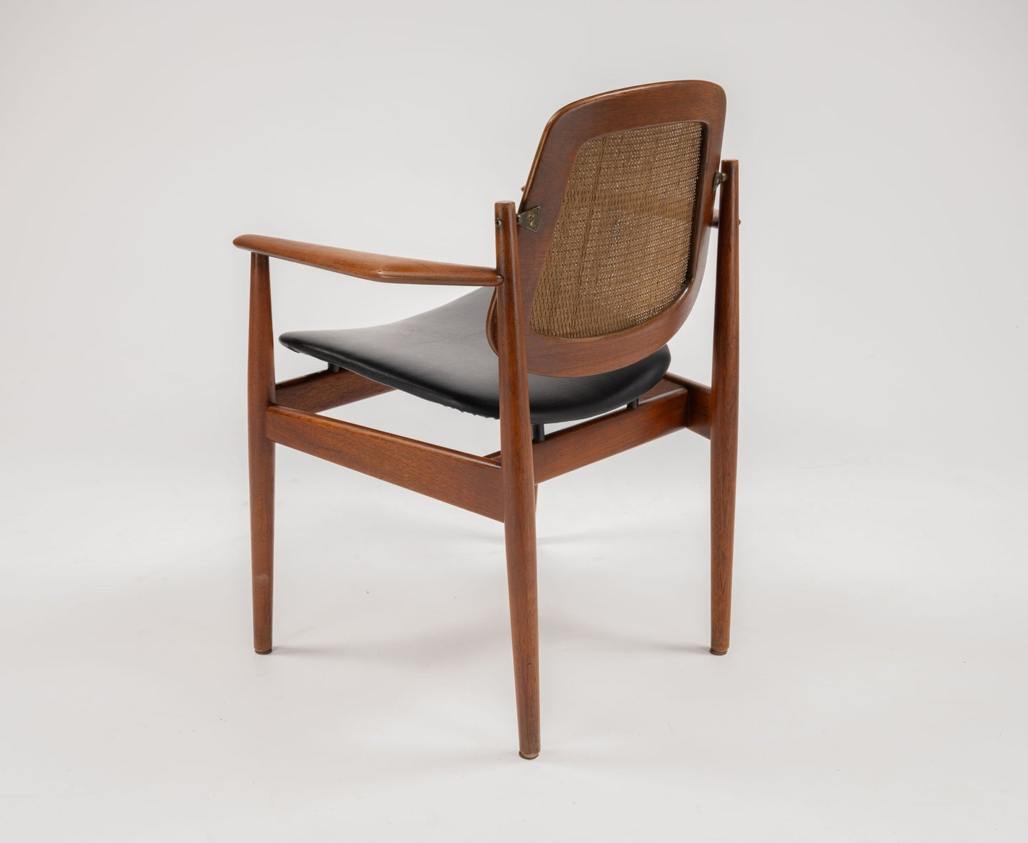Mid-century modern Arne Vodder dining chair with teak frame, cane backrest, black leather seat, and brass hinges.
