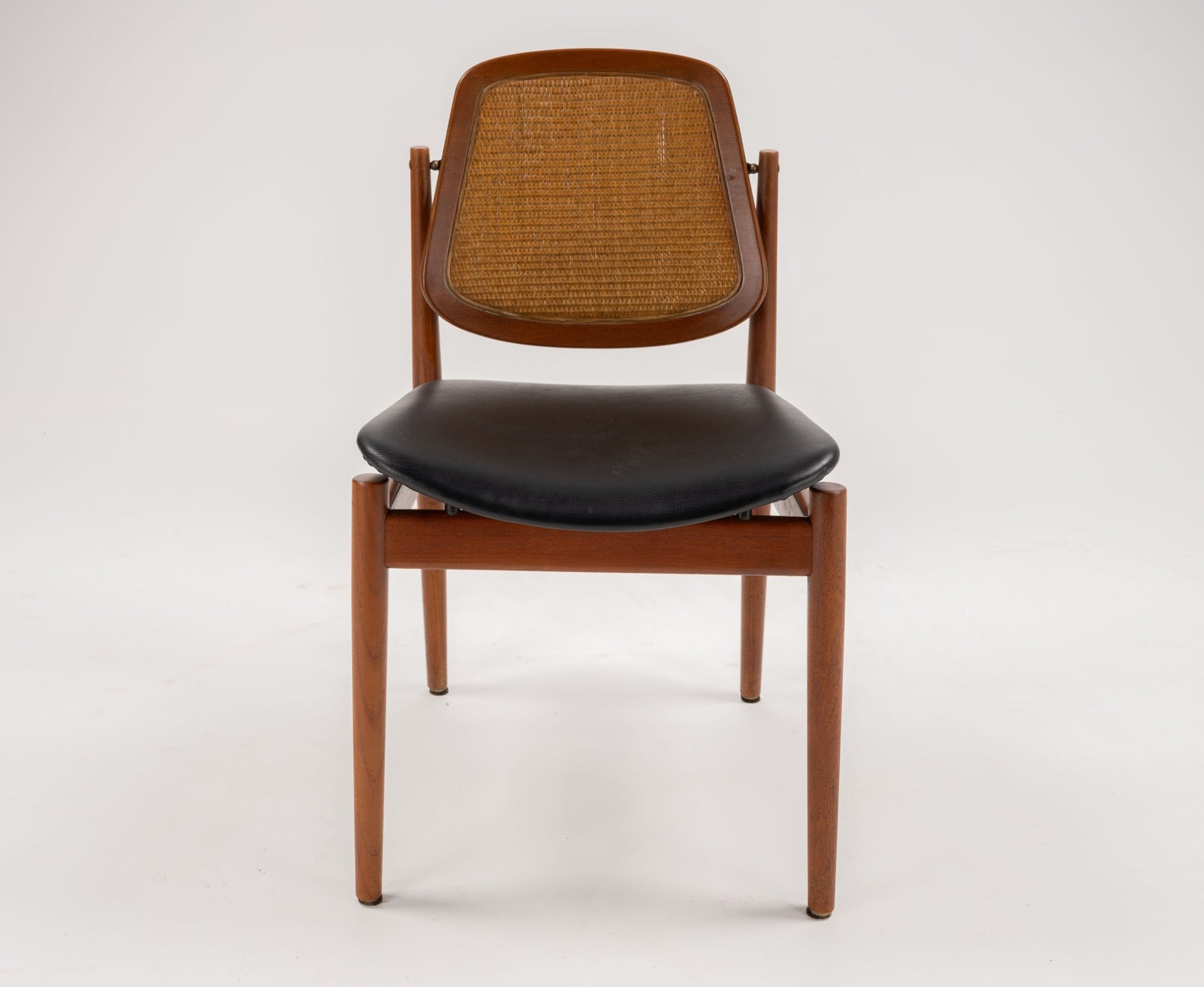 Arne Vodder Model 205 dining chair with teak frame, woven cane backrest, and black leather seat on white background
