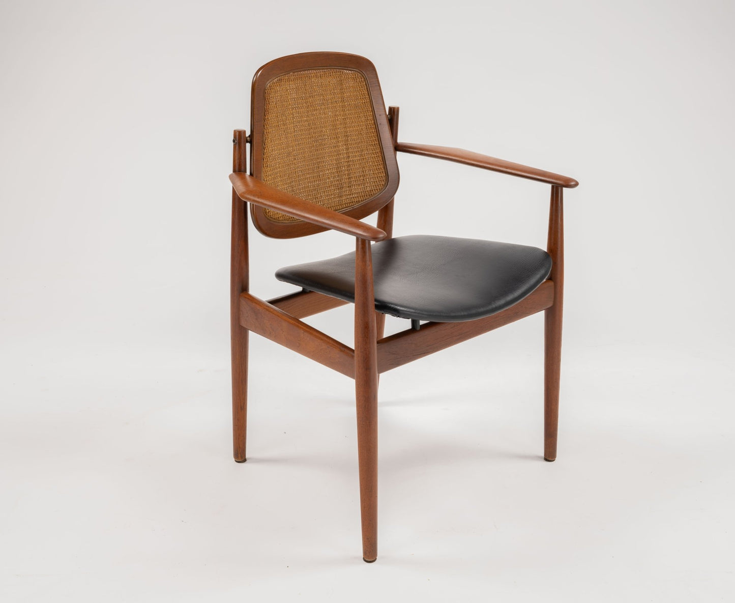 Mid-century modern Arne Vodder dining chair with teak frame, woven backrest, brass fittings, and black leather seat cushion.