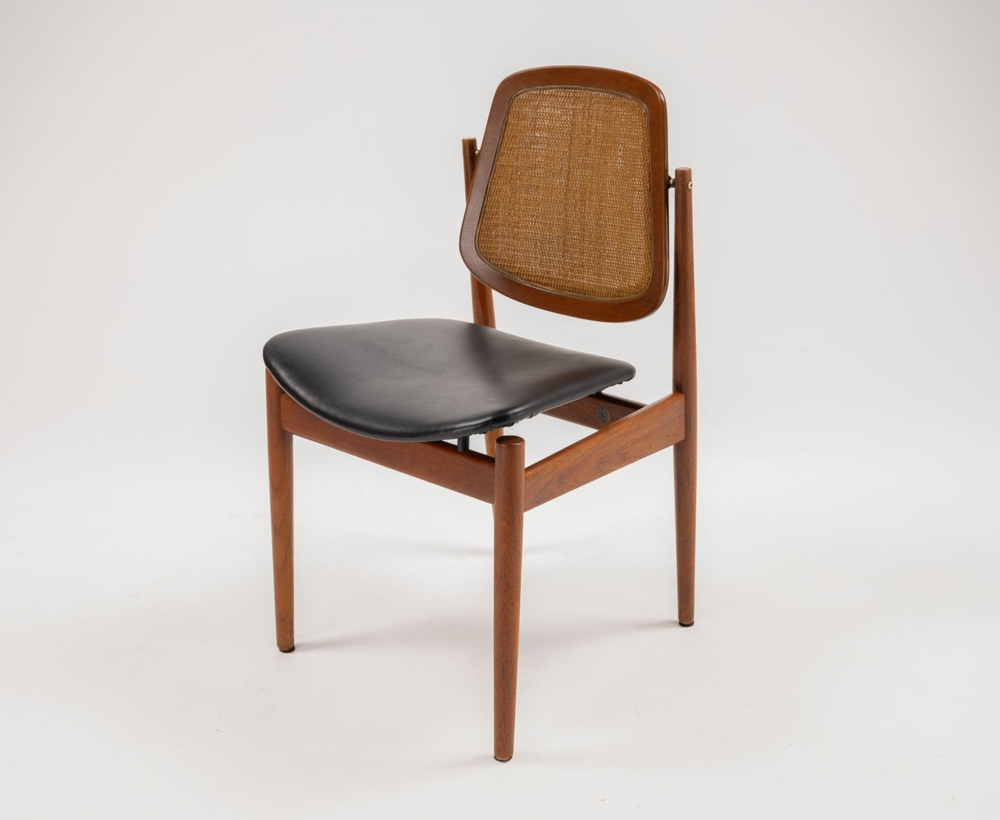 Mid-century modern Arne Vodder dining chair with teak frame, cane backrest, and black leather seat on white background.