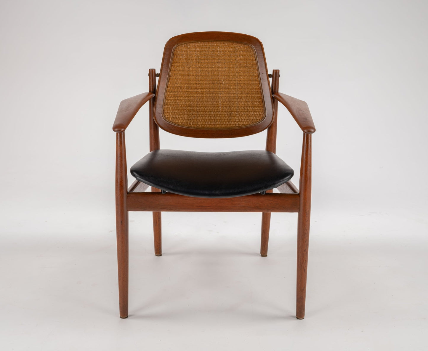 Mid-century modern teak dining chair with black leather seat, cane backrest, and sculpted wooden frame by Arne Vodder