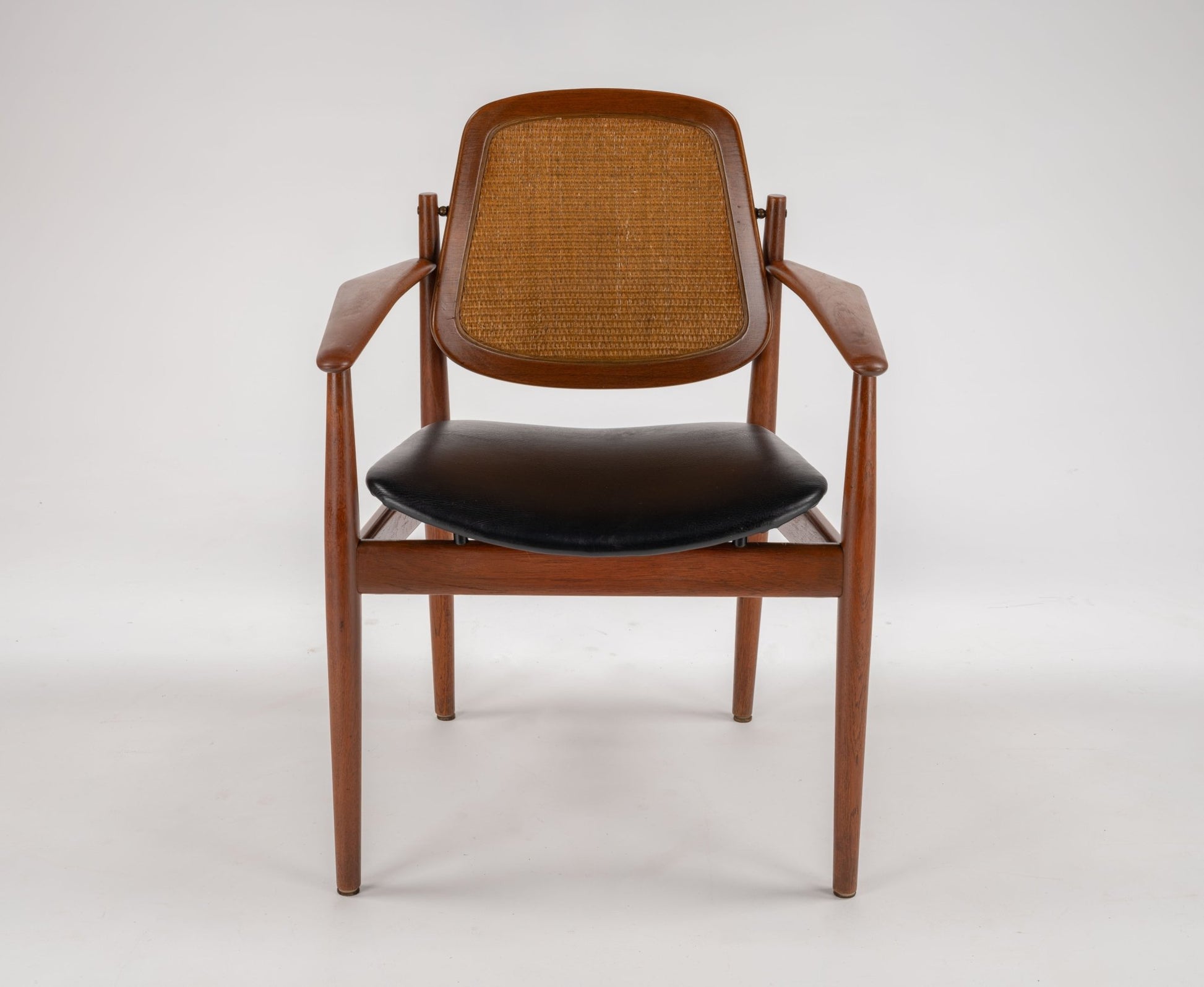 Mid-century modern teak dining chair with black leather seat, cane backrest, and sculpted wooden frame by Arne Vodder