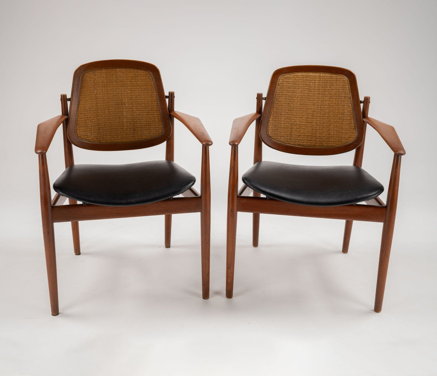 Pair of Arne Vodder Model 205 & 206 dining chairs with teak frames, cane backs, black leather seats, and brass fittings