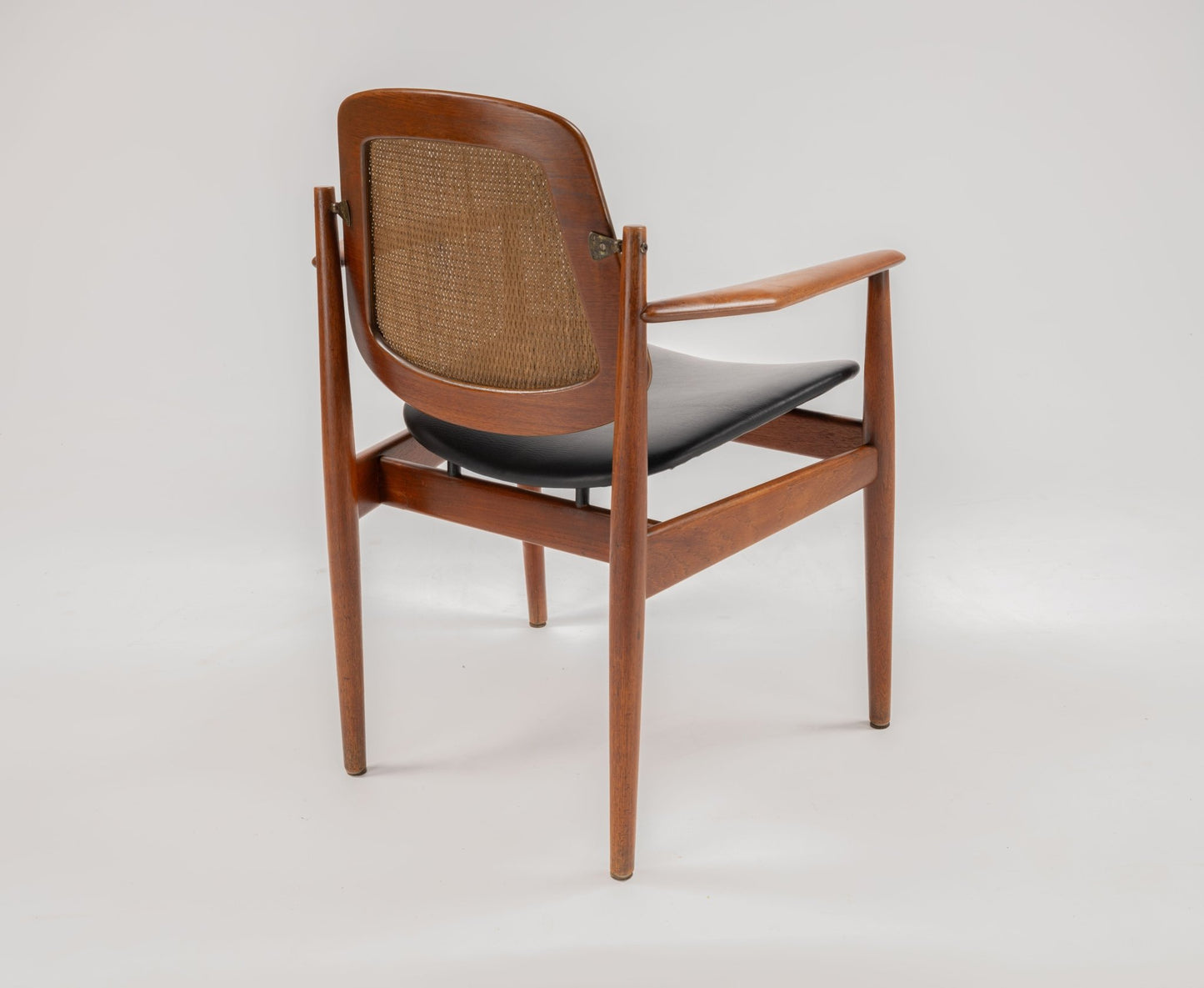 Arne Vodder Model 205 teak dining chair with cane backrest, hinged brass fittings, and black leather seat on white background