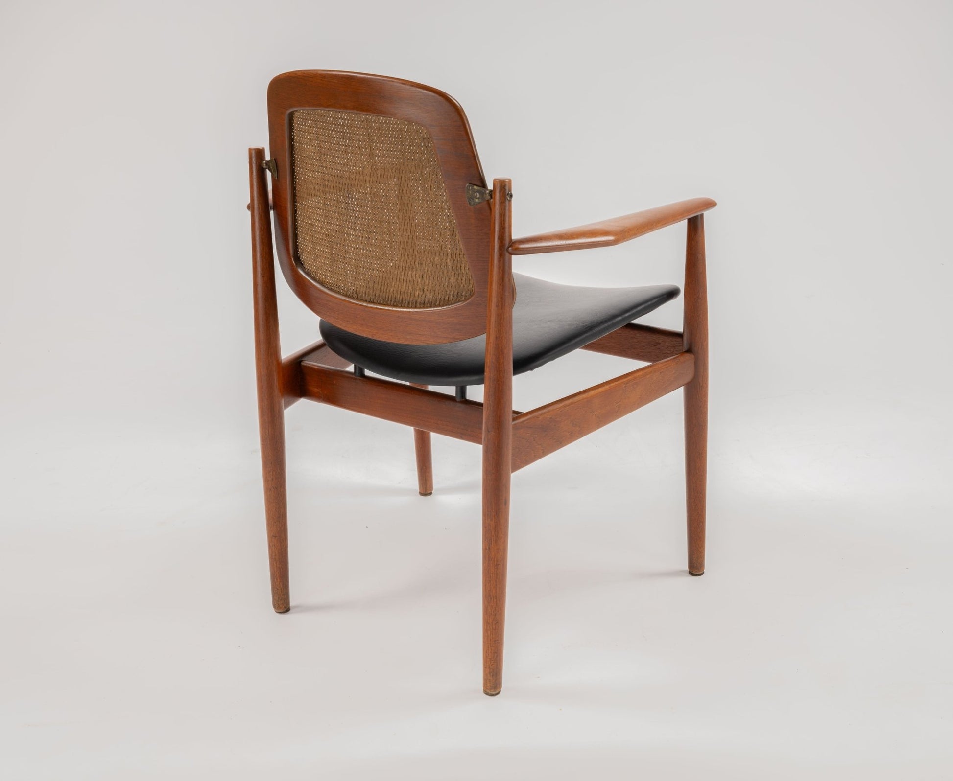 Arne Vodder Model 205 teak dining chair with cane backrest, hinged brass fittings, and black leather seat on white background