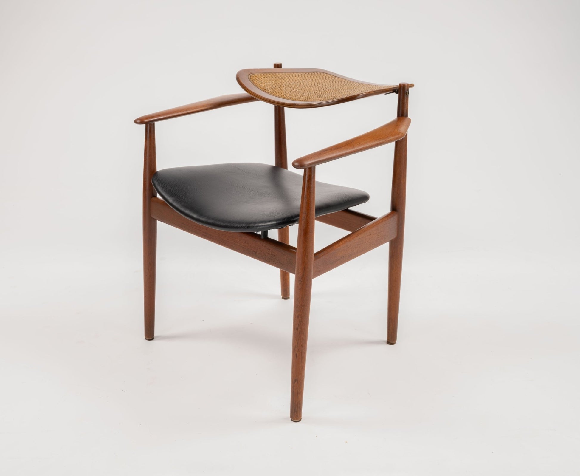 Mid-century modern Arne Vodder dining chair with teak frame, hinged cane backrest, and black leather seat cushion
