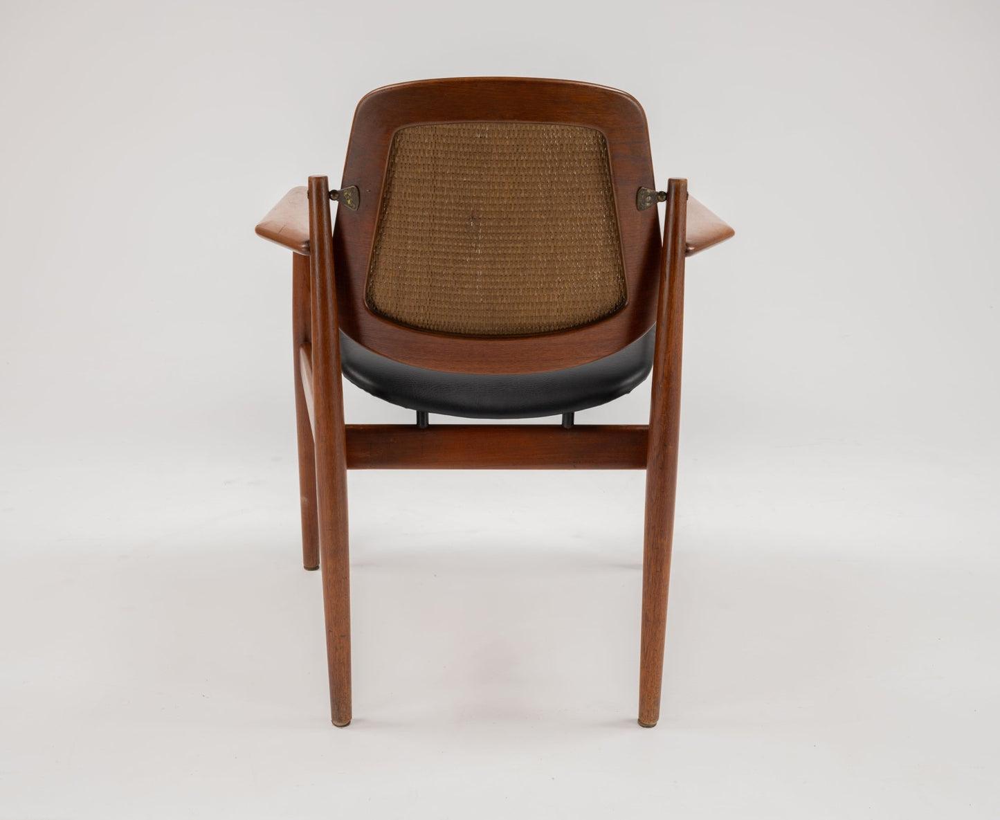 Mid-century modern Arne Vodder dining chair with teak frame, curved backrest, woven cane panel, and black seat cushion.