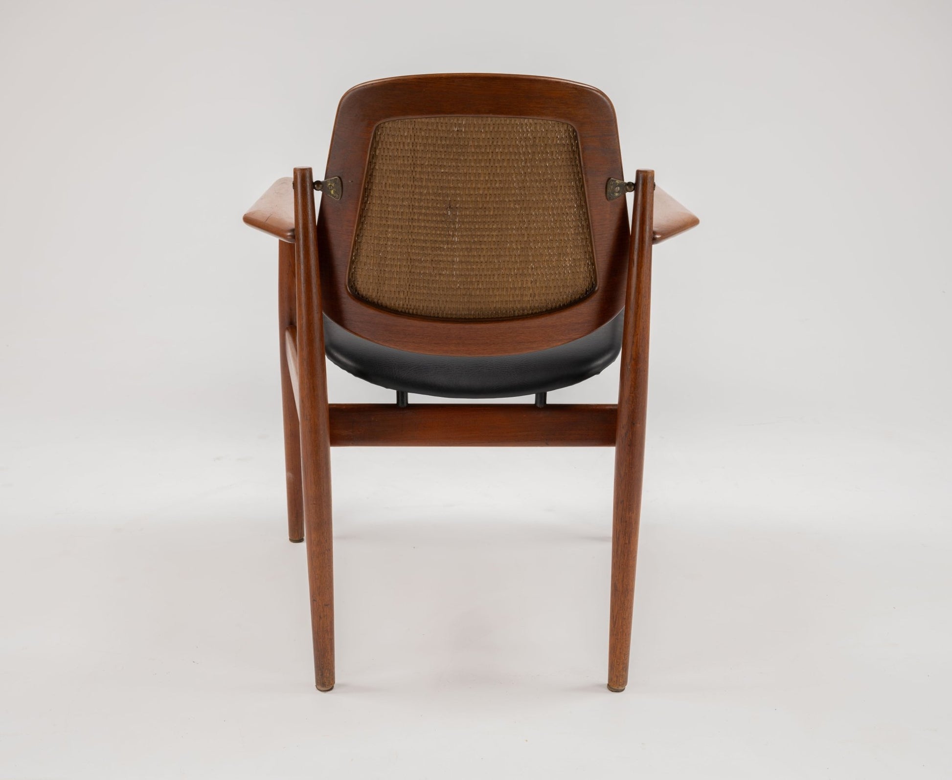 Mid-century modern Arne Vodder dining chair with teak frame, curved backrest, woven cane panel, and black seat cushion.
