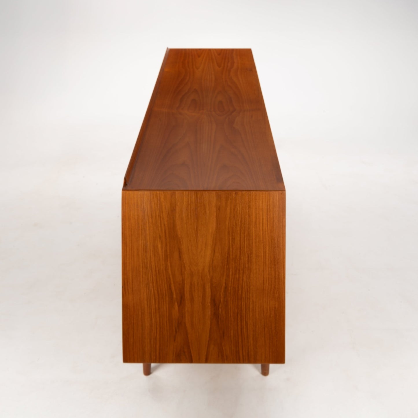 Arne Vodder Reversible-Drawer Teak Credenza for Sibast showing a side view of warm teak wood with a smooth finish and distinct grain pattern, highlighting its minimalist mid century modern design.