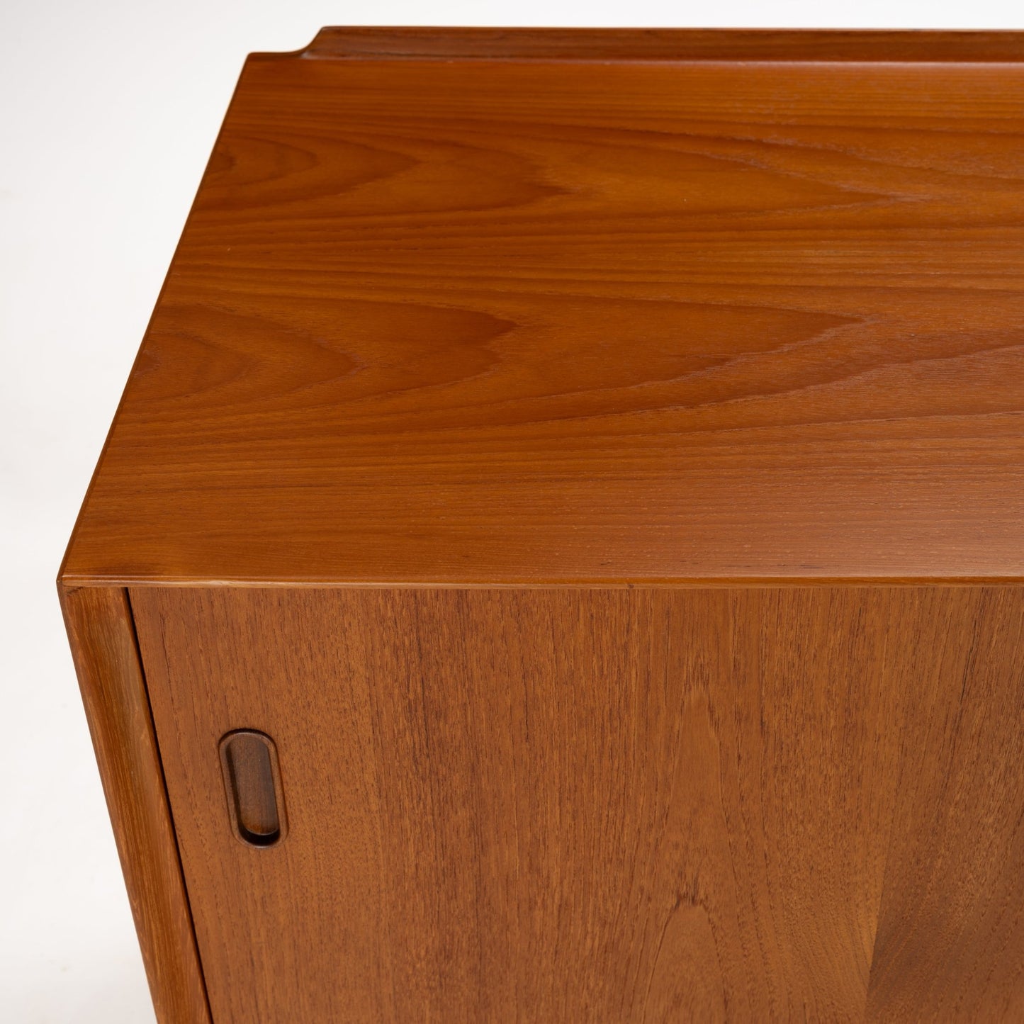 Arne Vodder Reversible-Drawer Teak Credenza for Sibast capturing the smooth teak wood surface with subtle grain patterns and the integrated recessed handle on the side panel in vintage mid century modern style.