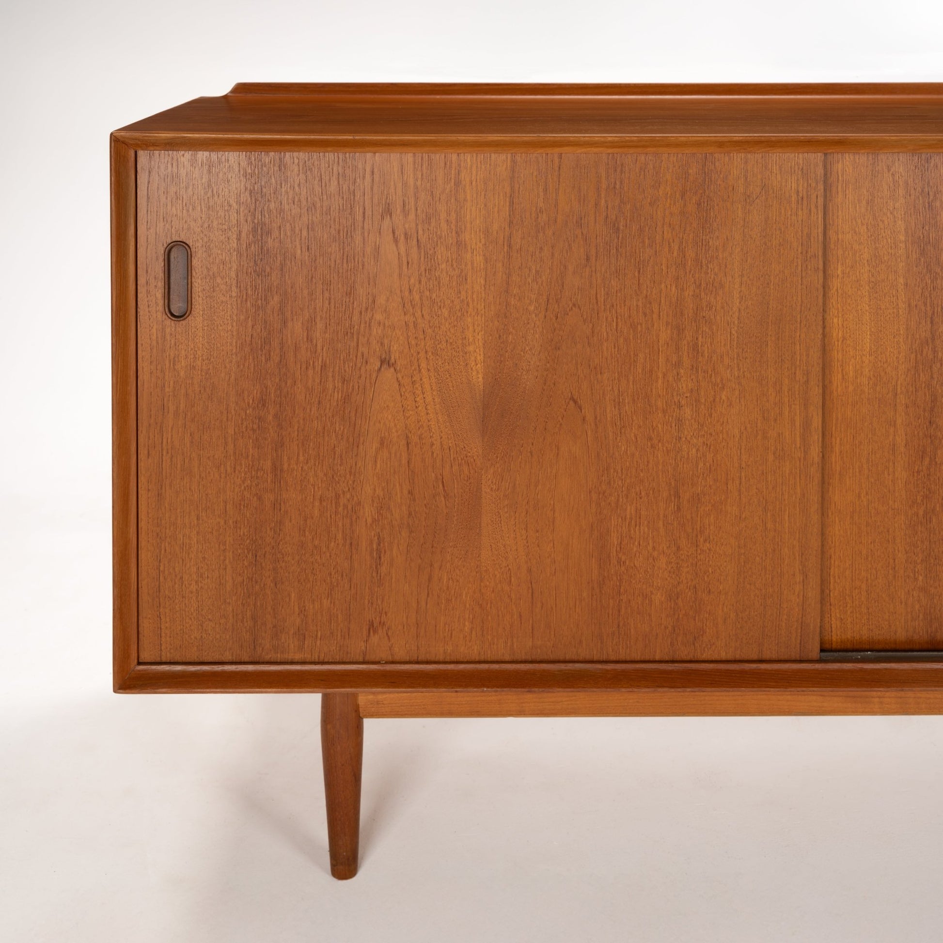 Arne Vodder Reversible-Drawer Teak Credenza for Sibast showcasing warm teak wood with a smooth sliding door, integrated recessed handle, and slender tapered legs in a mid century modern design.