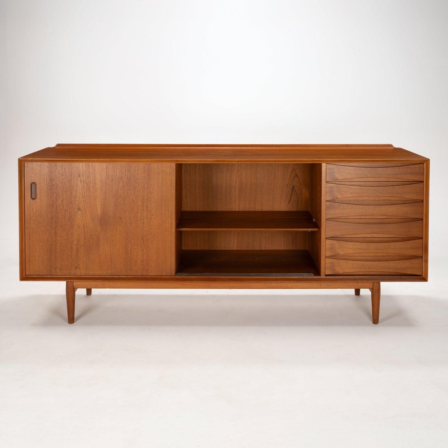 Arne Vodder Reversible-Drawer Teak Credenza for Sibast featuring warm teak wood with a spacious open shelving section, sculpted drawer fronts, and a sliding door on tapered legs in mid century modern style.