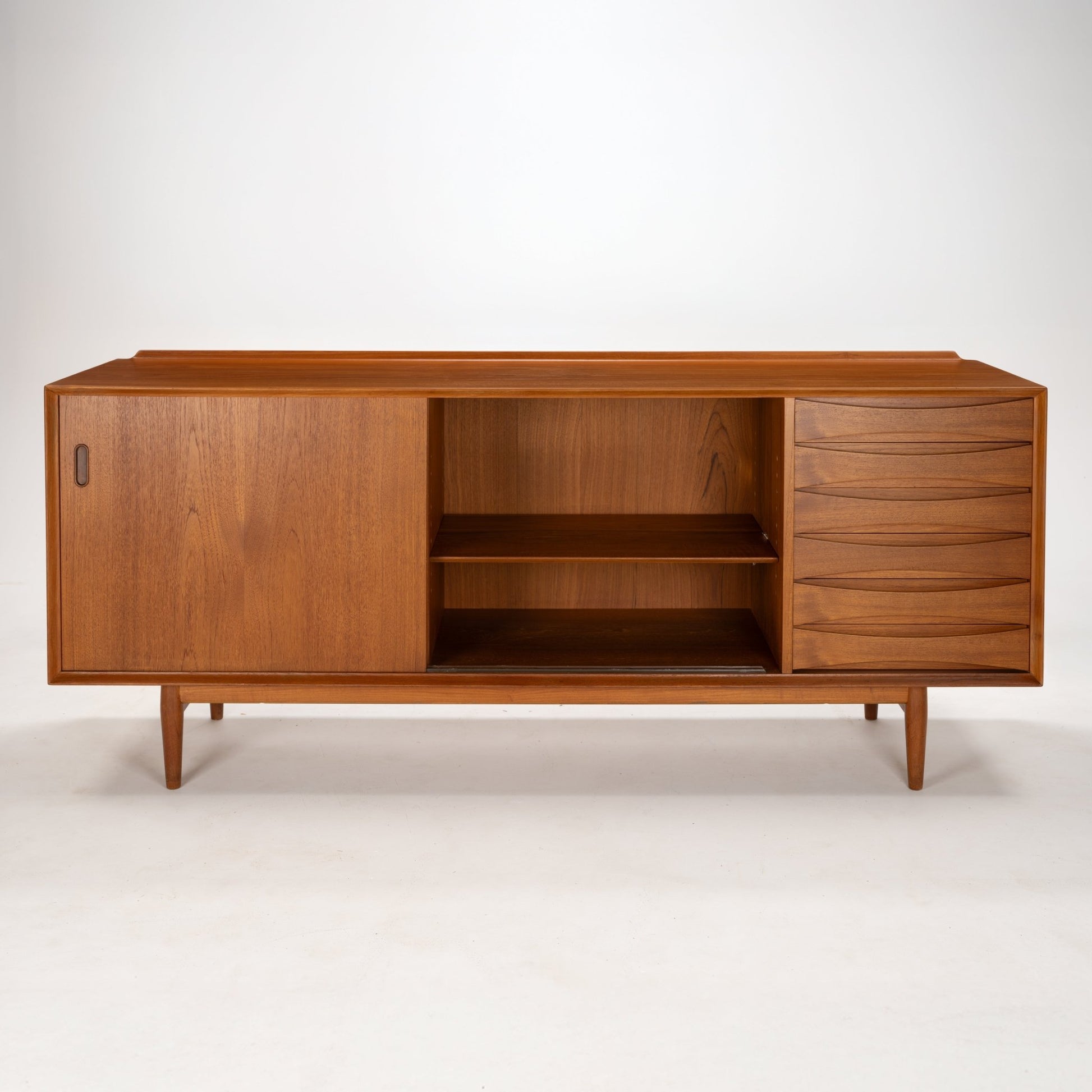 Arne Vodder Reversible-Drawer Teak Credenza for Sibast featuring warm teak wood with a spacious open shelving section, sculpted drawer fronts, and a sliding door on tapered legs in mid century modern style.