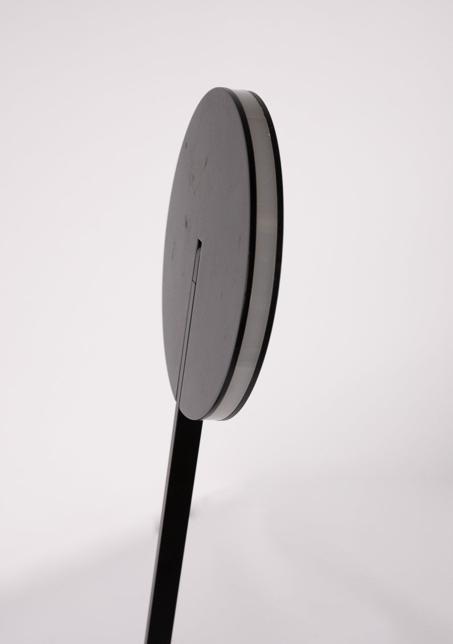 Close-up side view of Artemide Itis LED table lamp with thin circular head and slender black stem on white background.