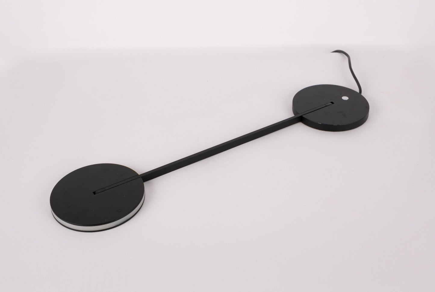 Pair of black Artemide Itis LED table lamps with slim connecting rod and circular bases on white background