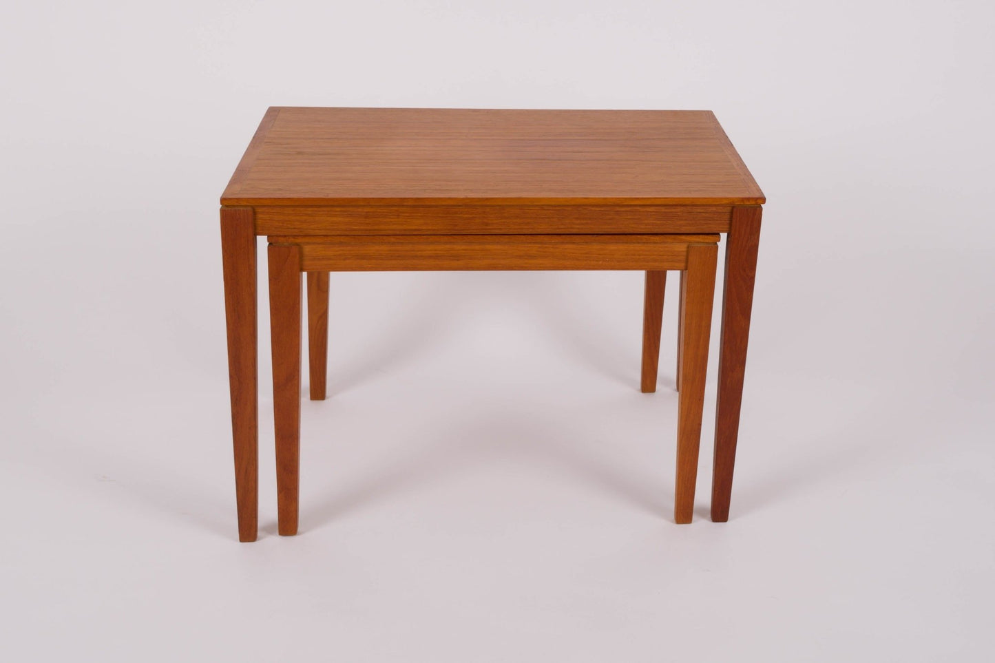 Pair of mid-century modern Bent Silberg nesting tables with tapered legs in teak wood on white background