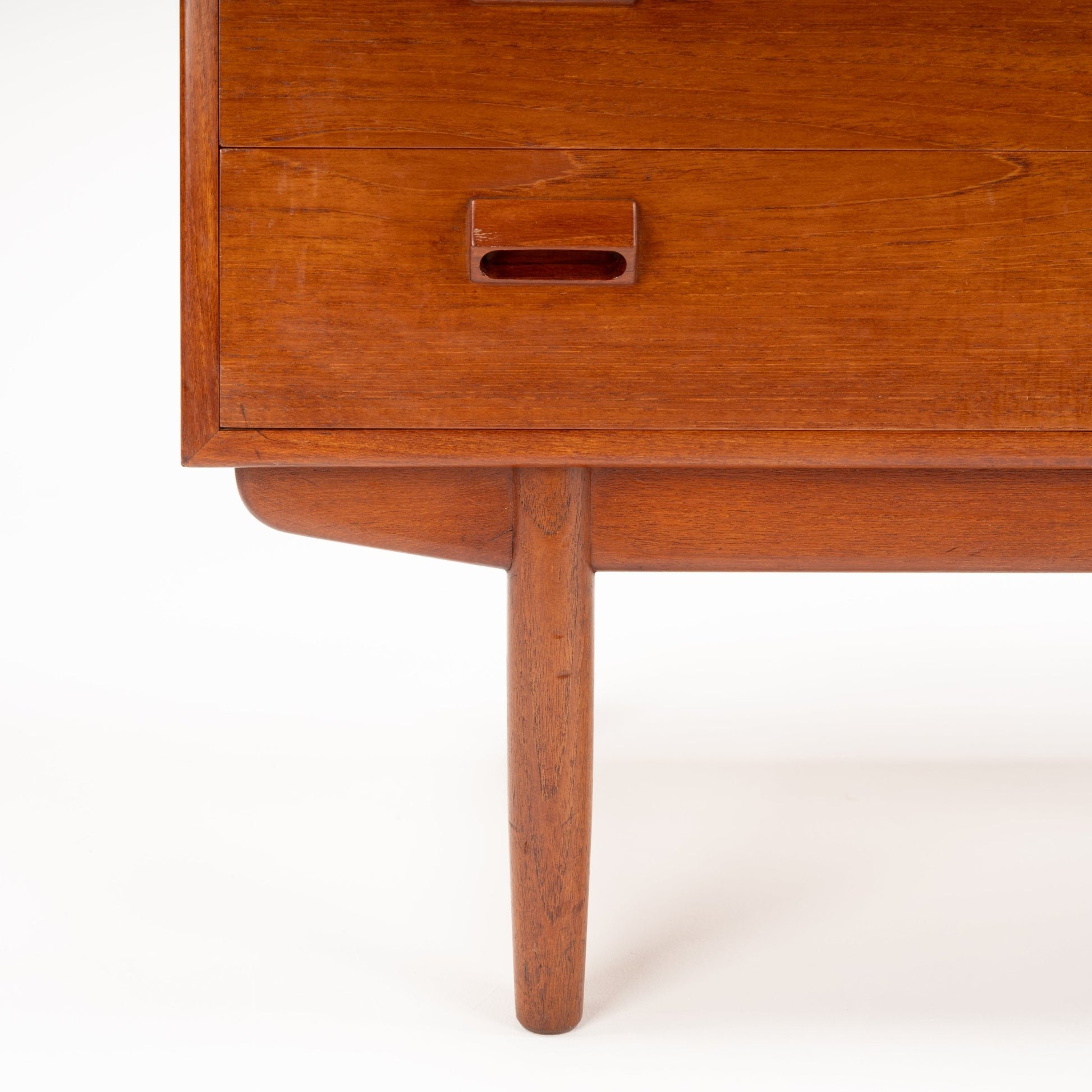 Close-up of mid-century wooden furniture leg and drawer with oval recessed handle in warm teak finish
