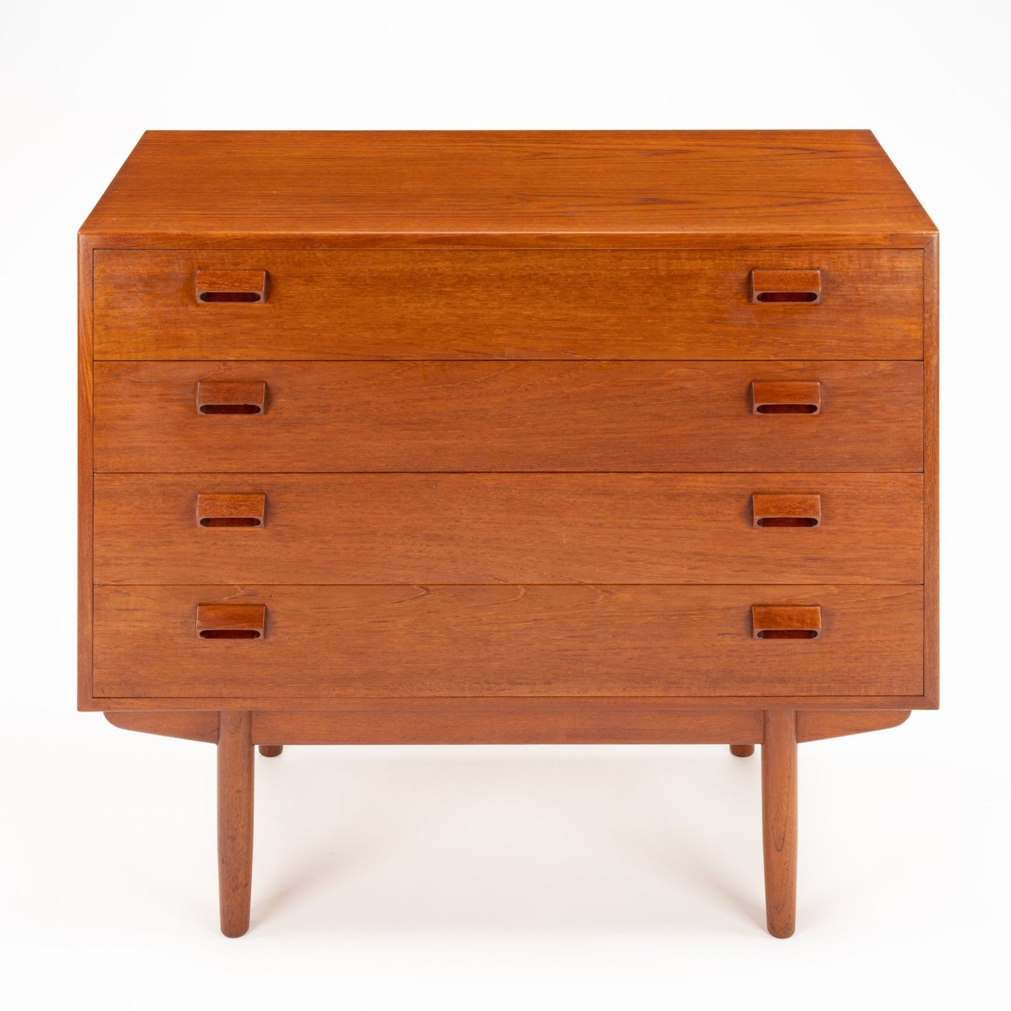 Front view of a wooden chest with four drawers featuring inset rectangular handles and slender tapered legs