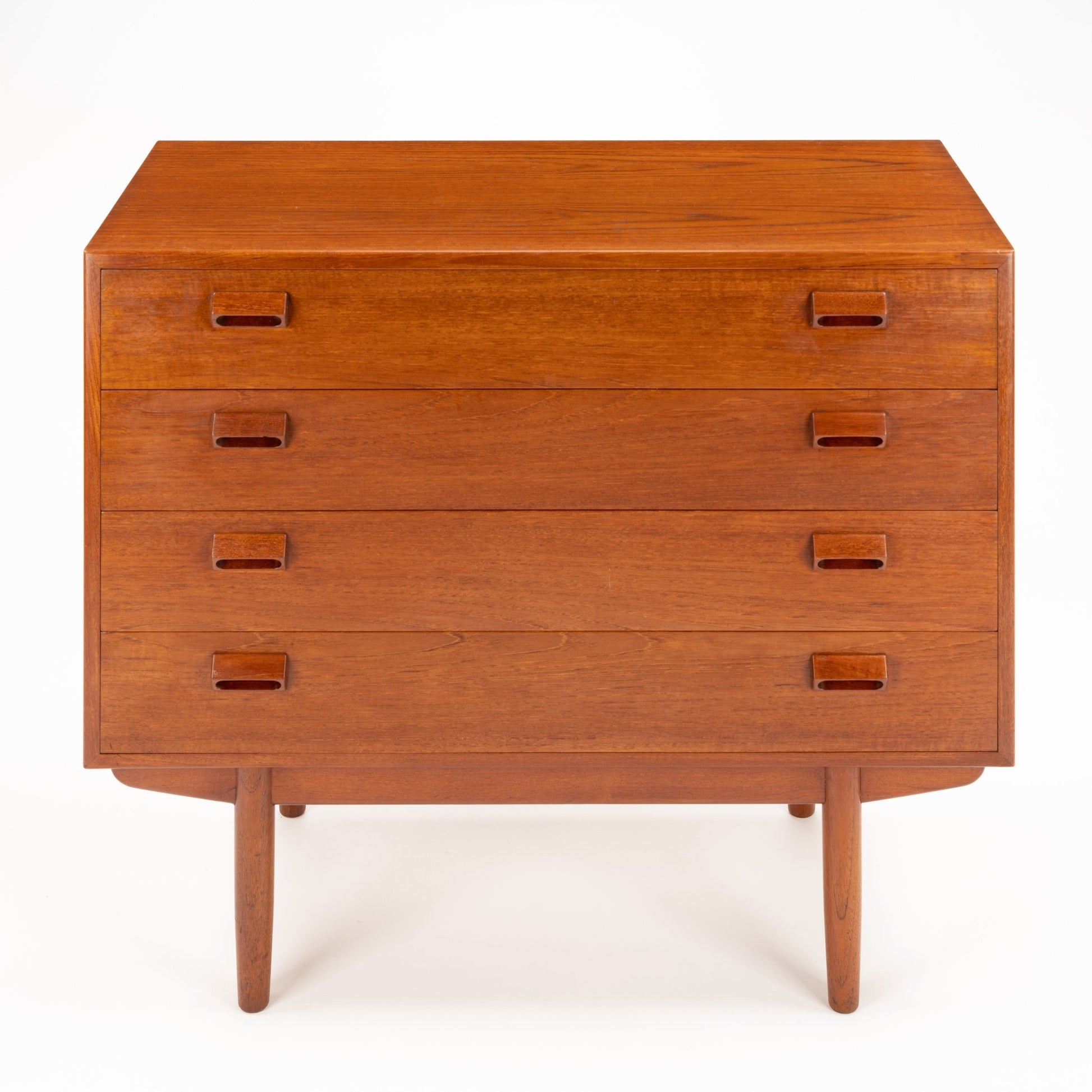 Front view of a wooden chest with four drawers featuring inset rectangular handles and slender tapered legs