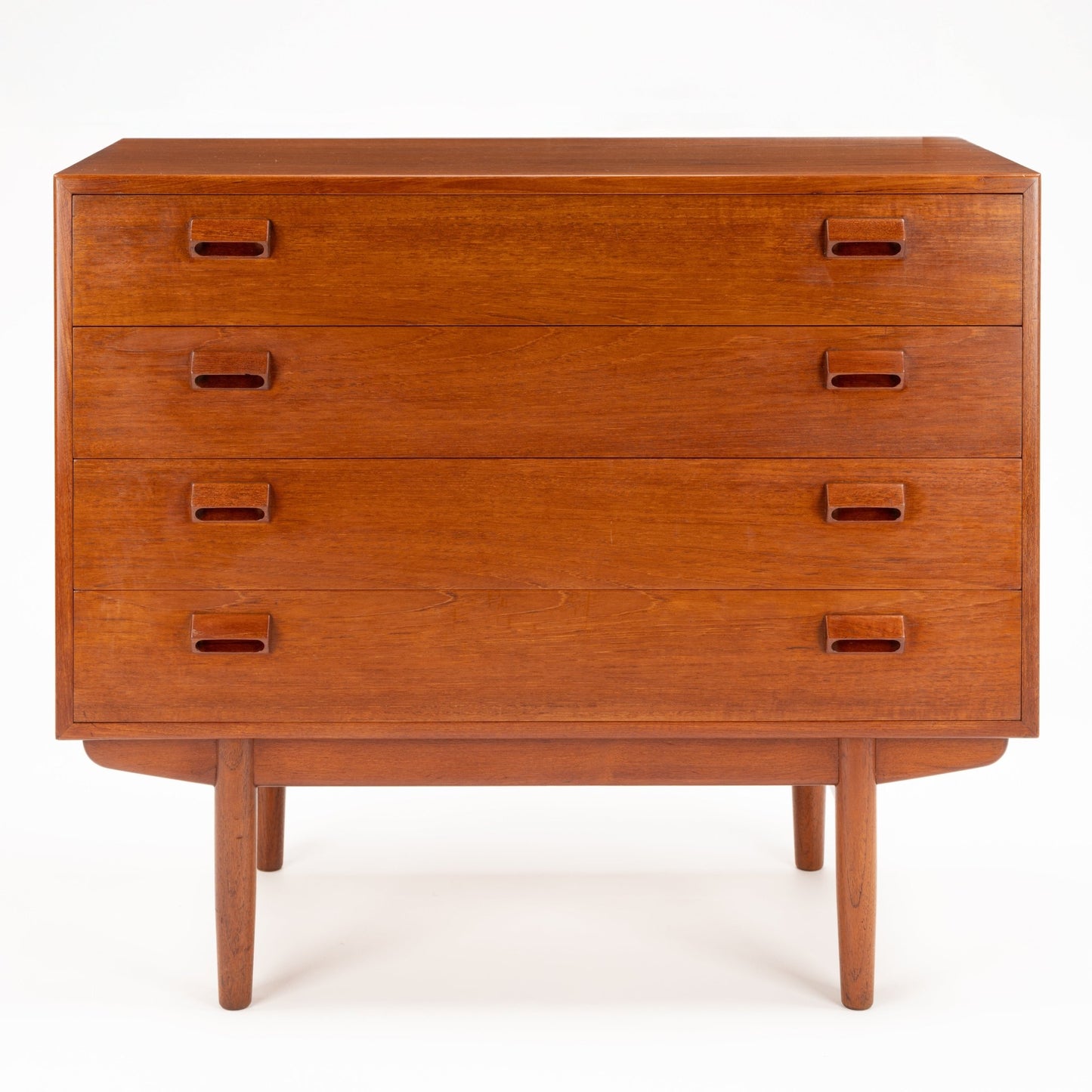 Minimalist mid-century wooden dresser with four drawers, integrated rectangular recessed handles, and tapered legs in warm finish