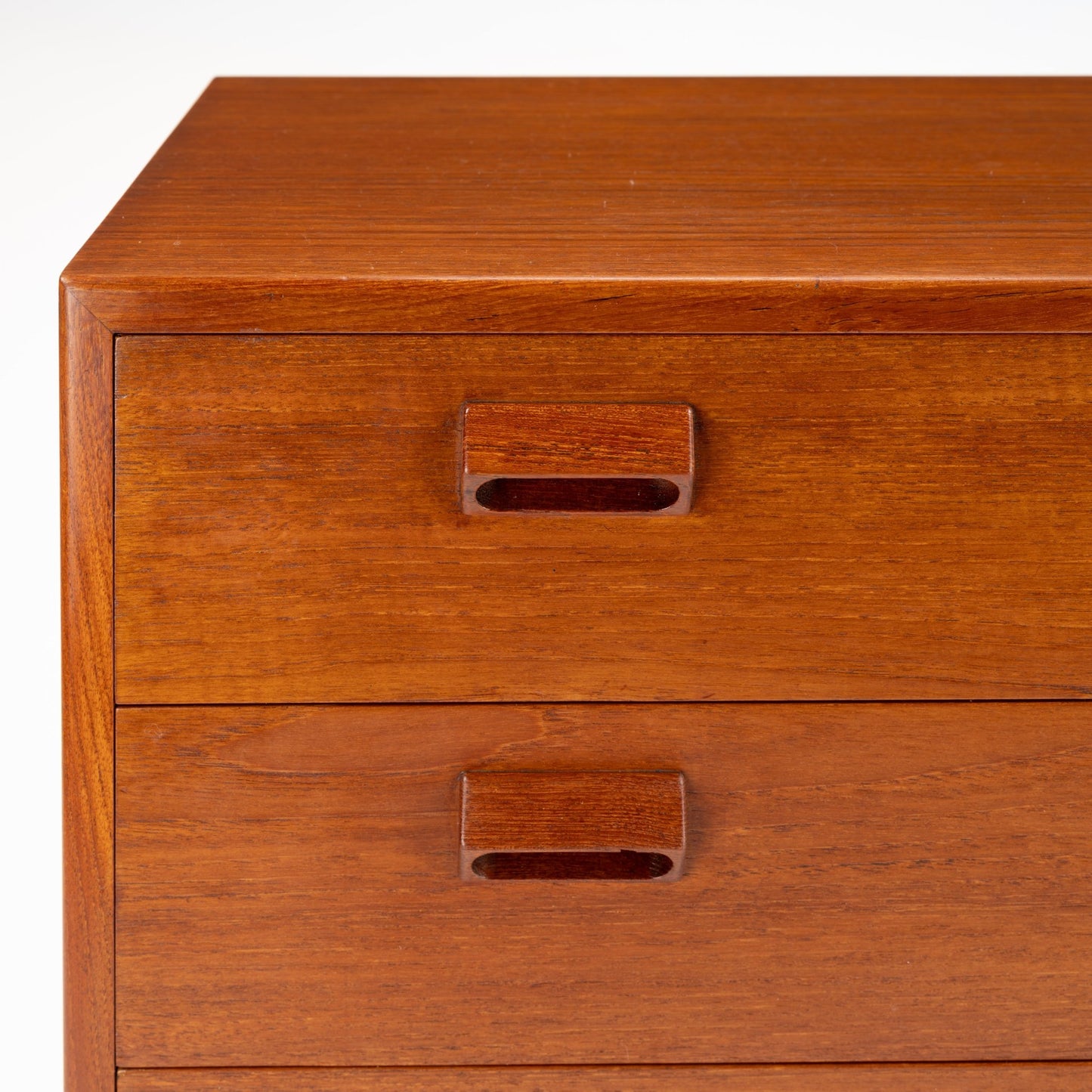 Close-up of two wooden drawers with integrated rectangular recessed handles in rich warm wood finish