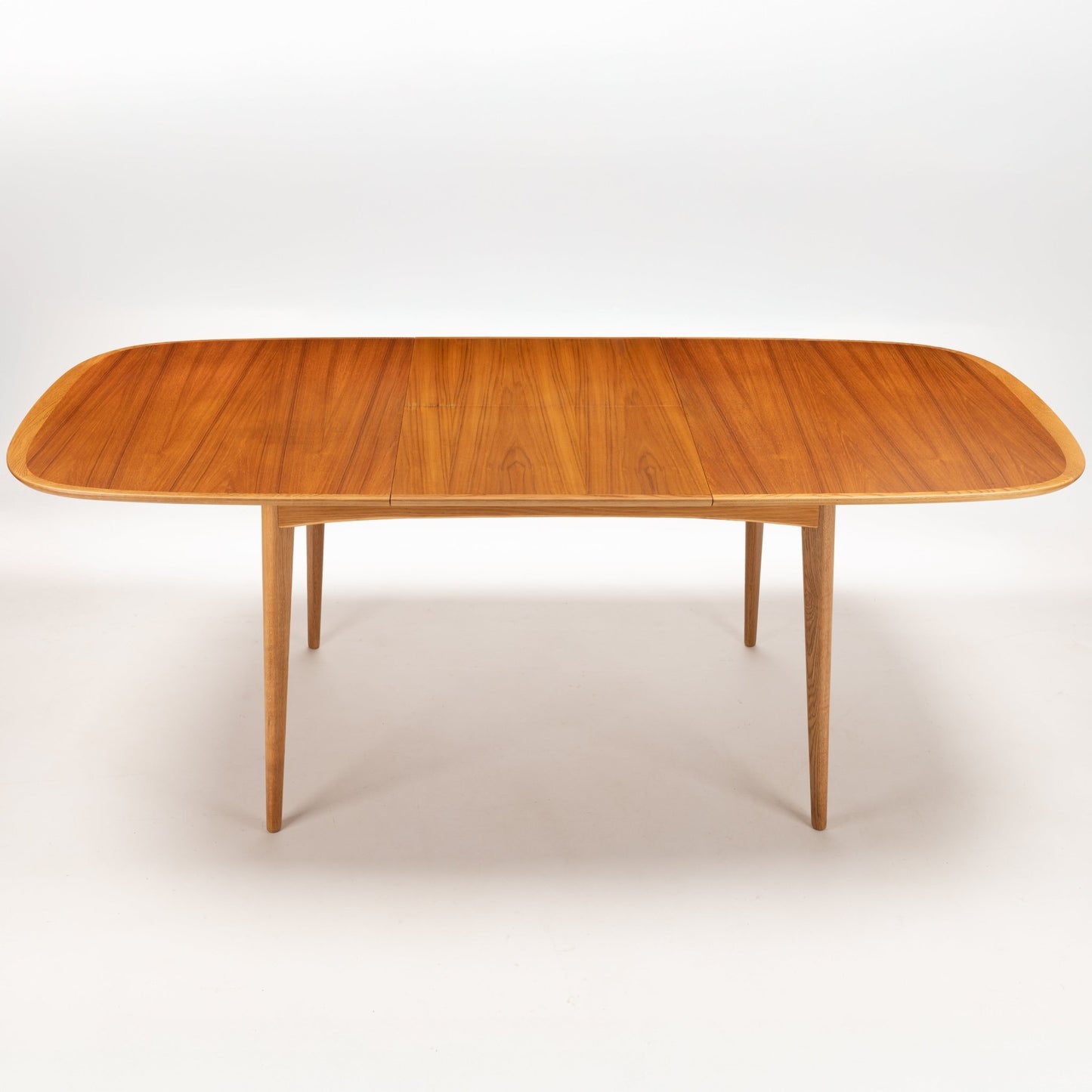 Danish Butterfly-Leaf Teak Dining Table with rounded oval top tapered legs and rich polished wood grain in vintage Danish furniture style