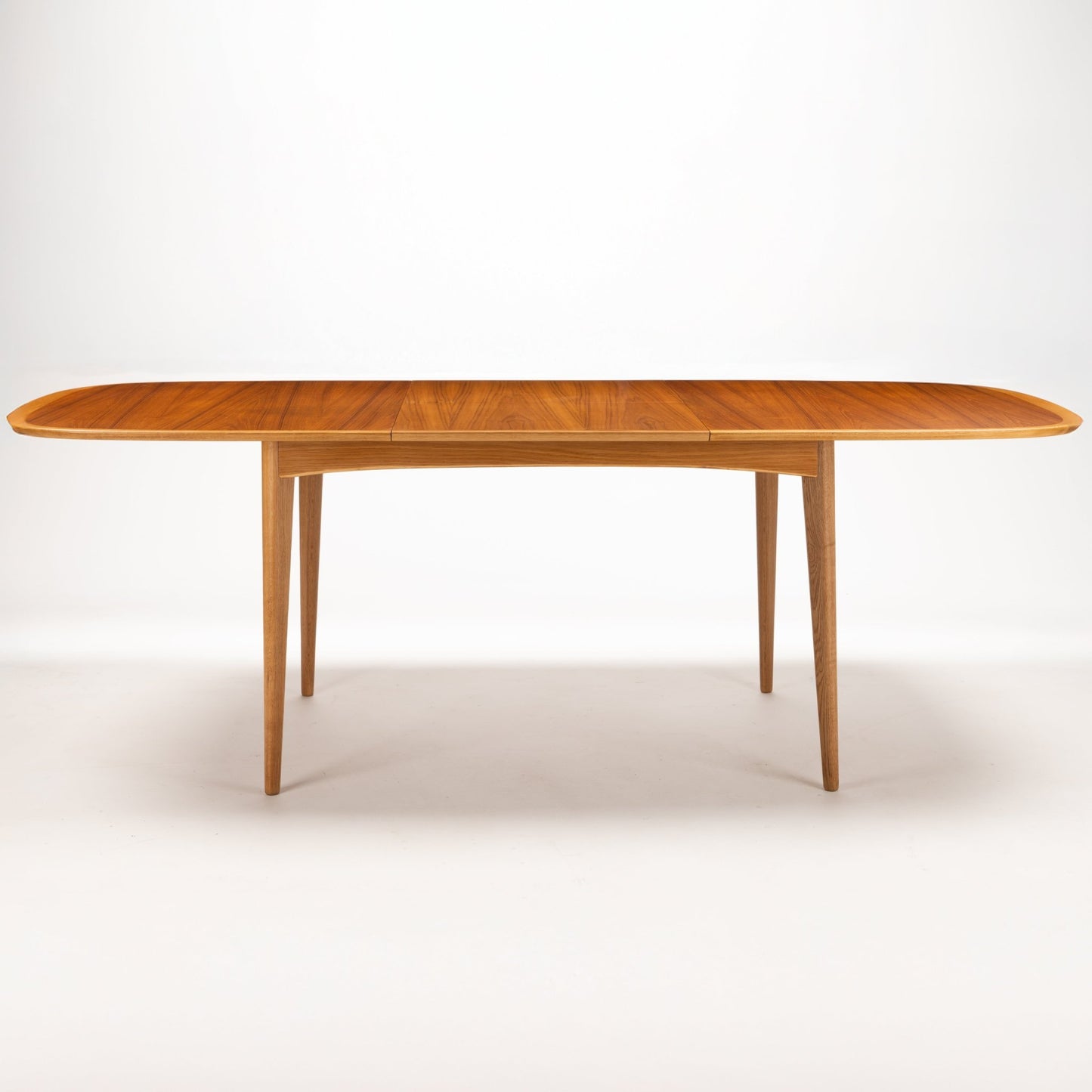 Danish Butterfly-Leaf Teak Dining Table with elongated oval top slender tapered legs and warm polished wood grain in vintage Danish furniture style