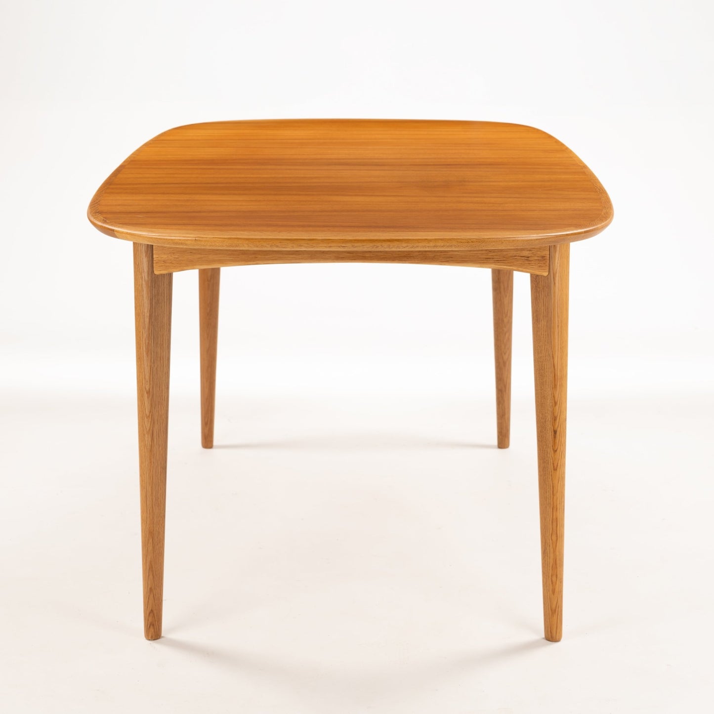 Danish Butterfly-Leaf Teak Dining Table with rounded corners slender tapered legs and rich linear teak grain in vintage Danish furniture style