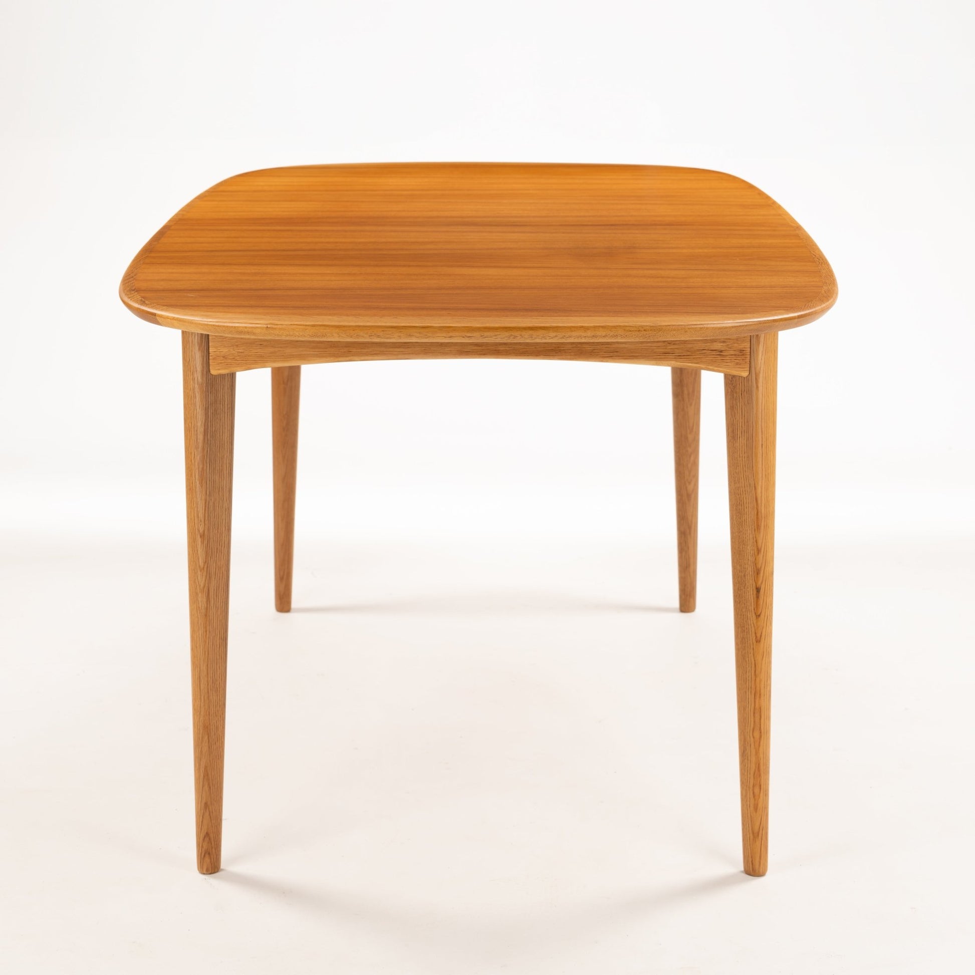 Danish Butterfly-Leaf Teak Dining Table with rounded corners slender tapered legs and rich linear teak grain in vintage Danish furniture style