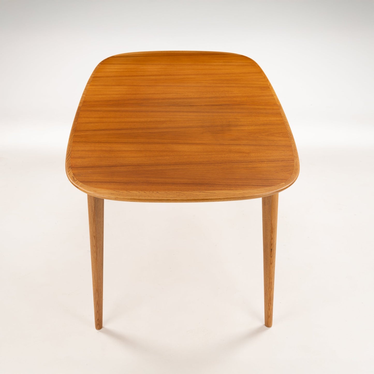 Danish Butterfly-Leaf Teak Dining Table showing a rounded rectangular top tapered legs and glowing teak grain in vintage Danish furniture style