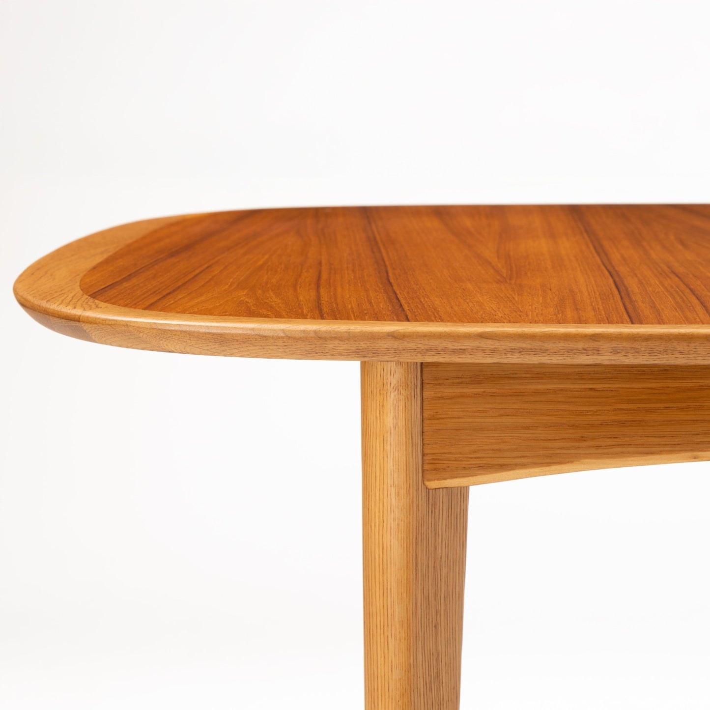 Danish Butterfly-Leaf Teak Dining Table detail showing rounded tabletop edge tapered leg and apron with rich linear teak grain in vintage Danish furniture style